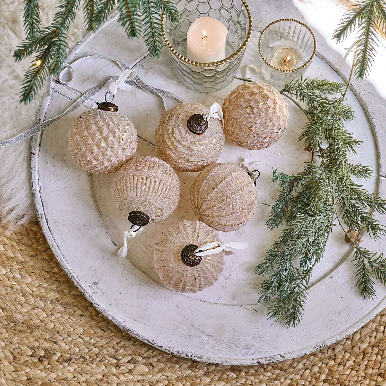 Lot de 6 boules de Noël Eirelyn Ensemble de six boules de Noël en verre rose doré sur un plateau blanc avec branches de sapin décoratives