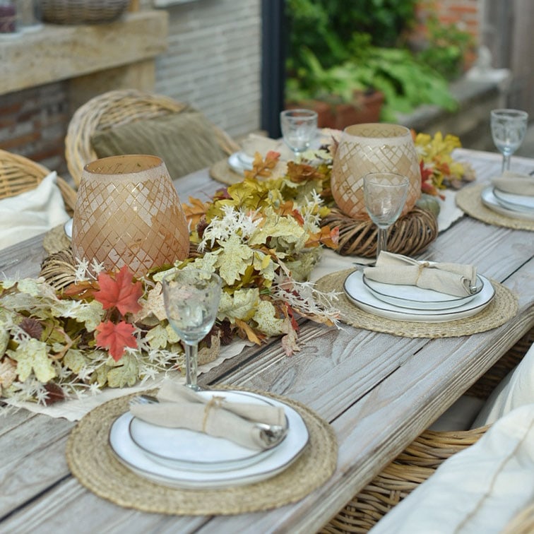Table rustique en bois décorée de feuilles naturelles et de lanternes en rotin pour une ambiance chaleureuse