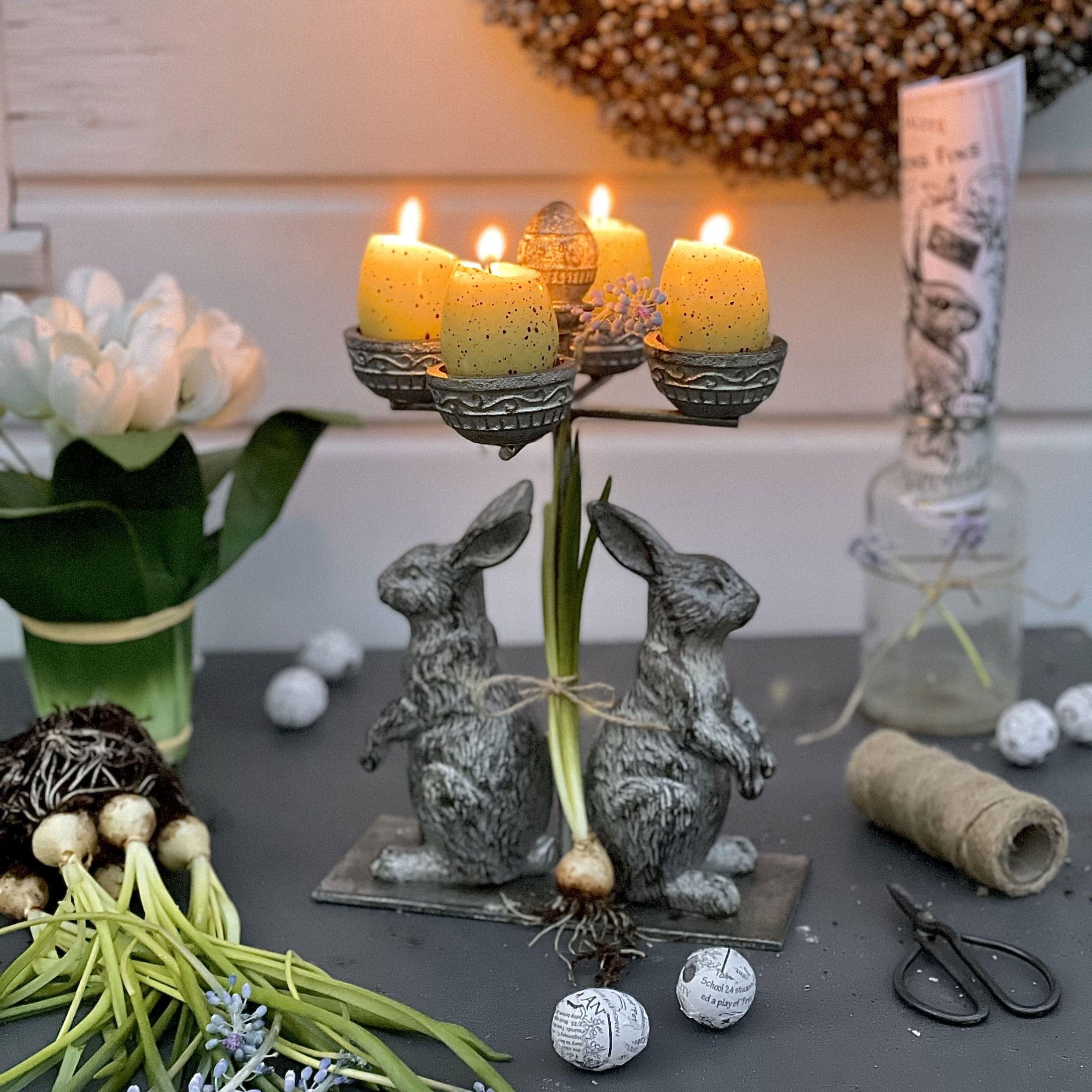 Bougeoir en métal avec deux lapins et bougies jaunes pour décoration printanière de table