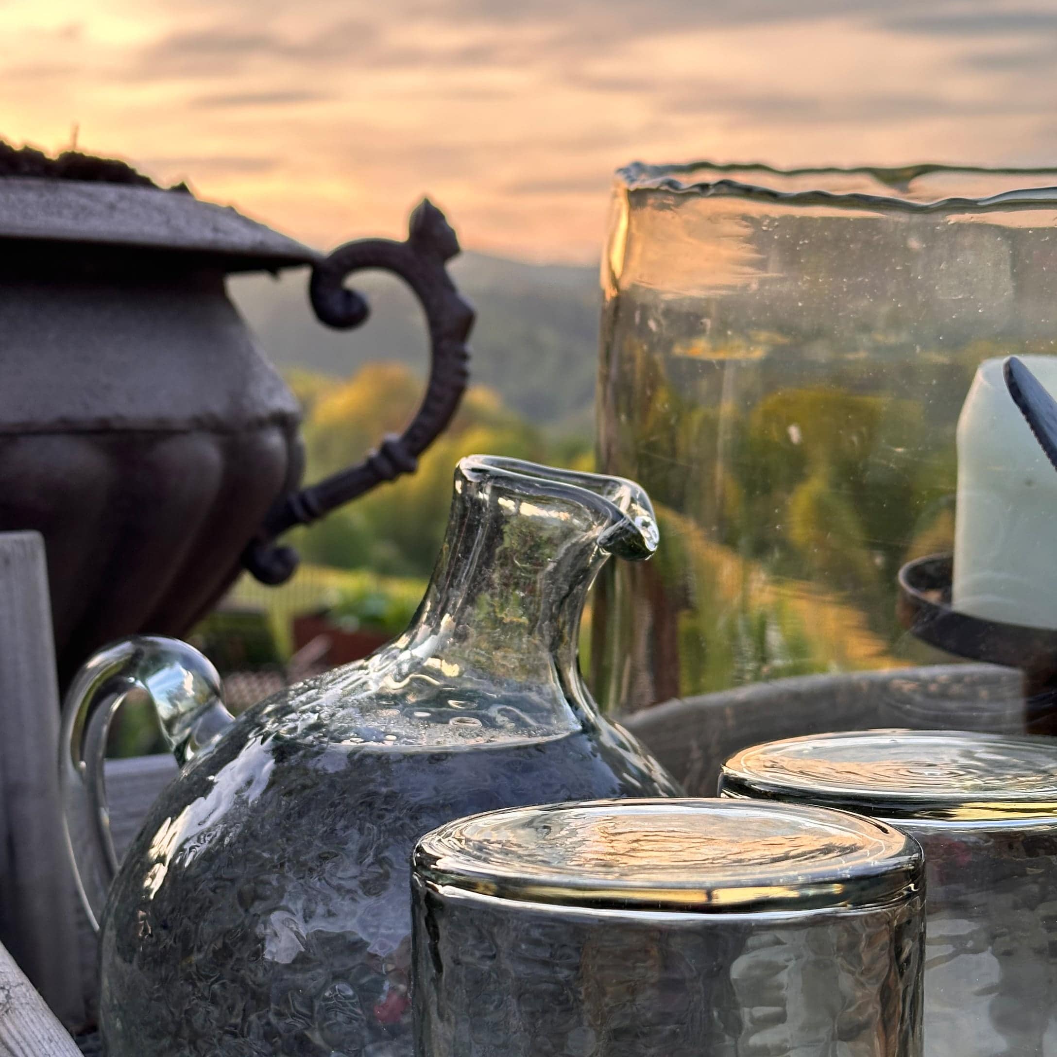 Carafe et verres en verre texturé dans un jardin d'été au coucher du soleil