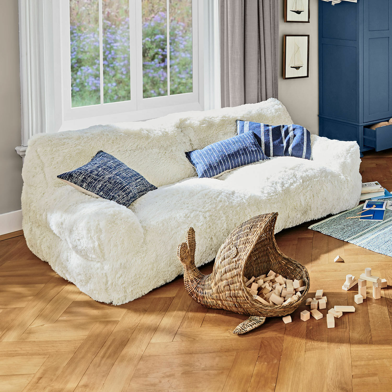 Canapé pour enfants Cerveteri Canapé blanc en fausse fourrure avec coussins bleus dans un salon lumineux au sol en bois