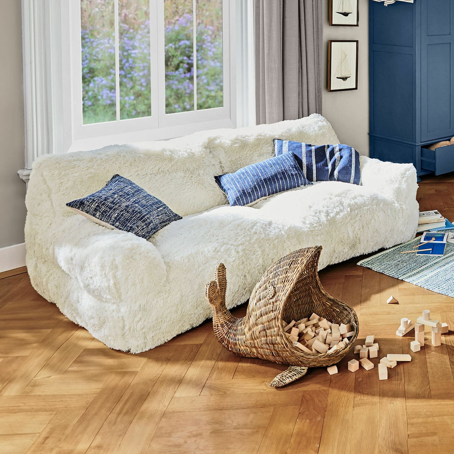 Canapé pour enfants Cerveteri Canapé blanc en fausse fourrure avec coussins bleus dans un salon lumineux au sol en bois