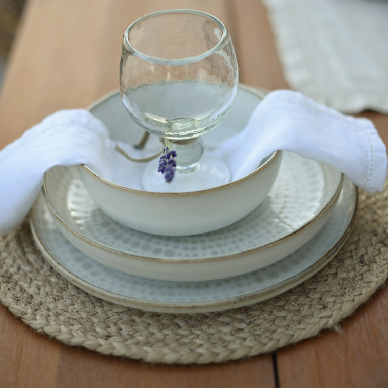 Ensemble de vaisselle en céramique blanche avec assiettes et bol sur un dessous de table tressé avec serviette blanche