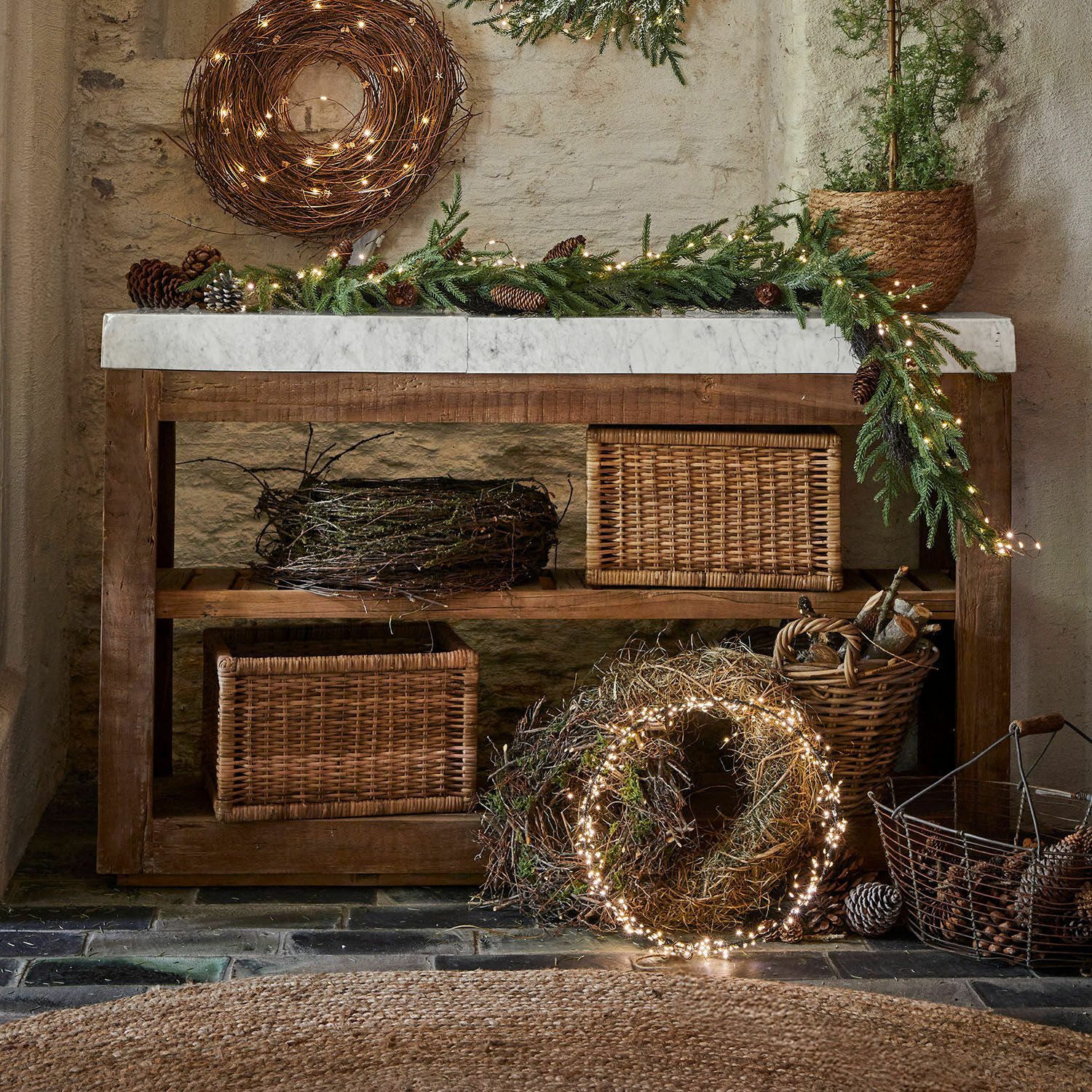 Console Tresienne Table rustique en bois avec plateau en marbre et décorations de Noël en branches et guirlandes lumineuses LED