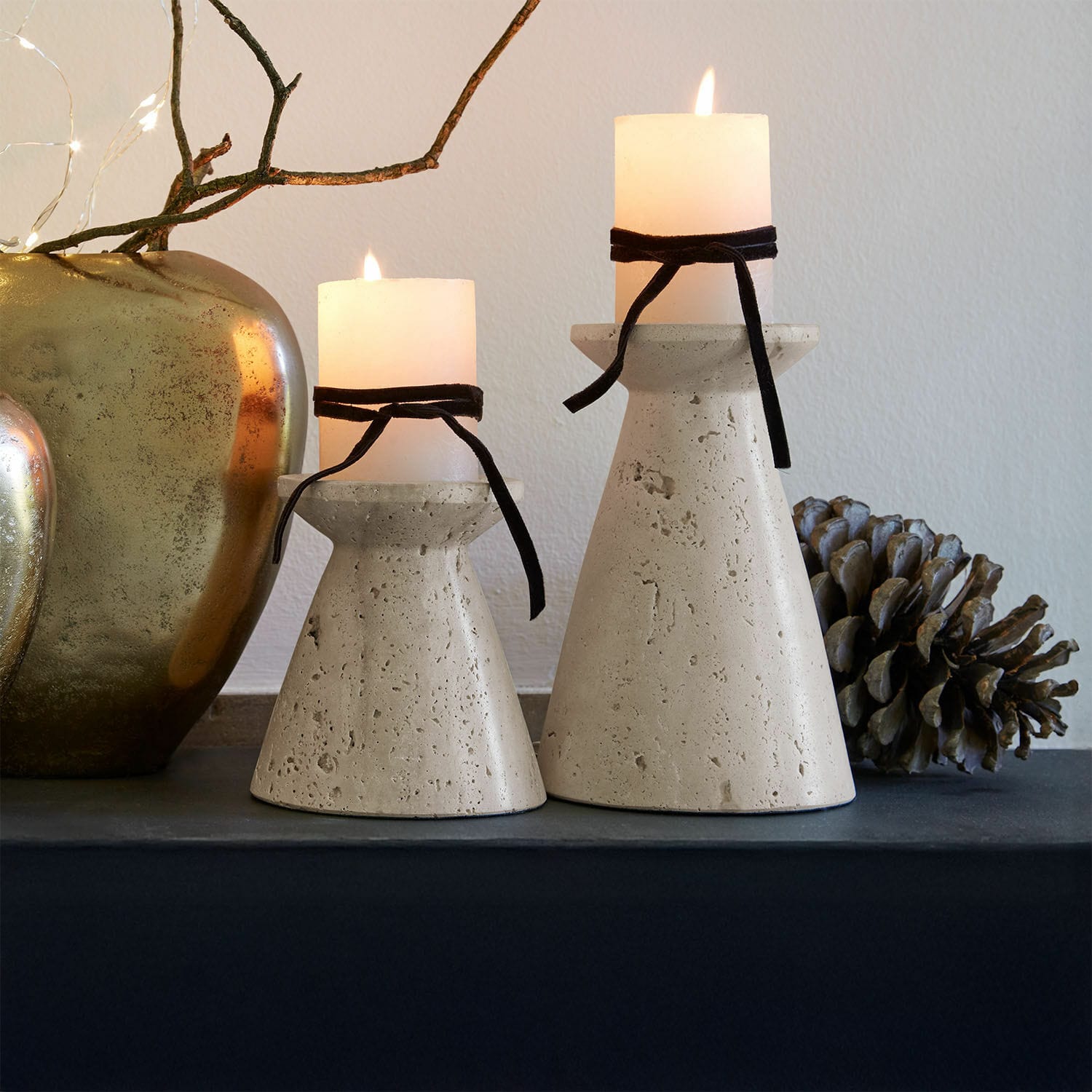 Lot de 2 bougeoirs Bazrahim Deux bougeoirs en béton beige avec bougies blanches et rubans noirs sur une table décorative