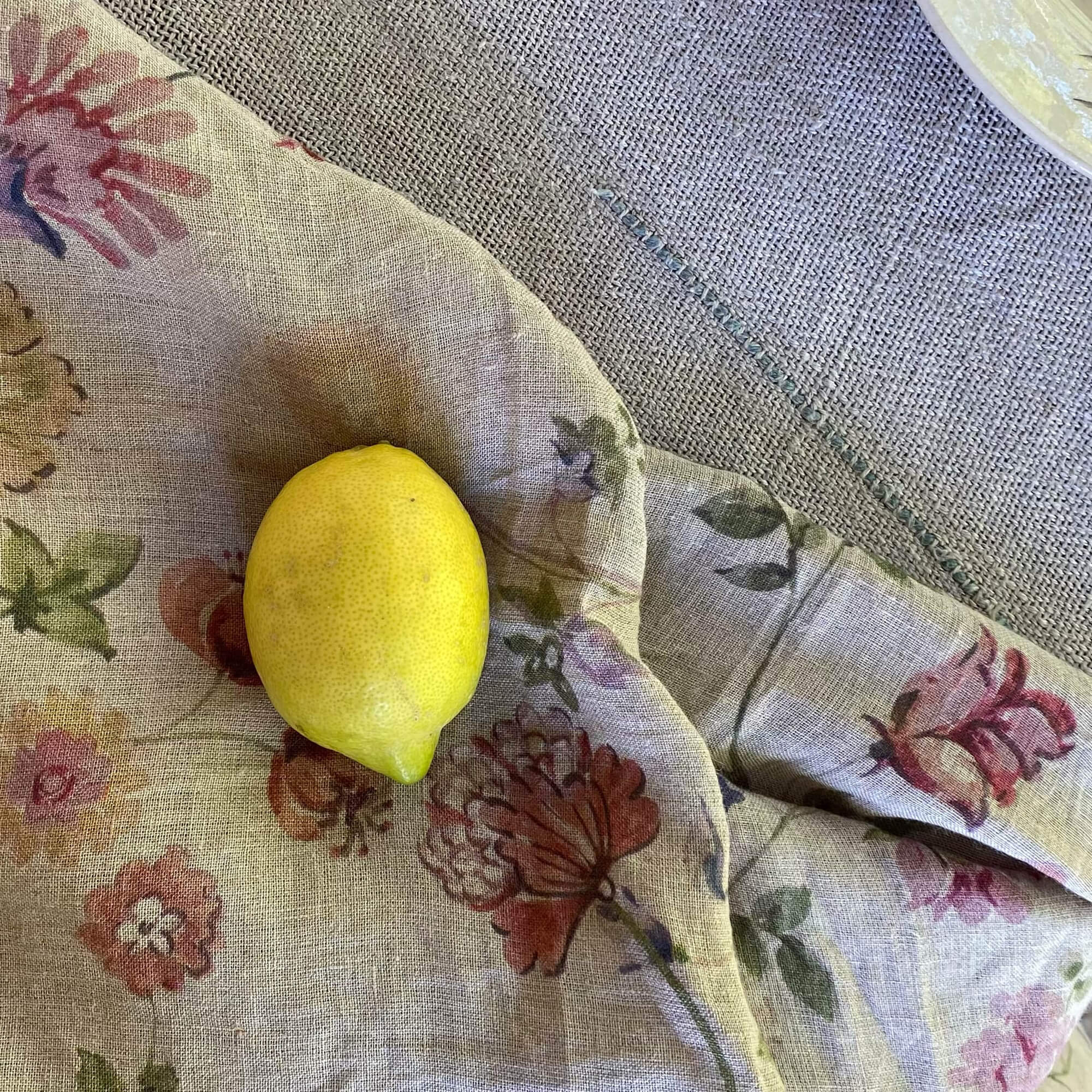 Nappe en lin à motif floral pastel avec un citron jaune posé dessus