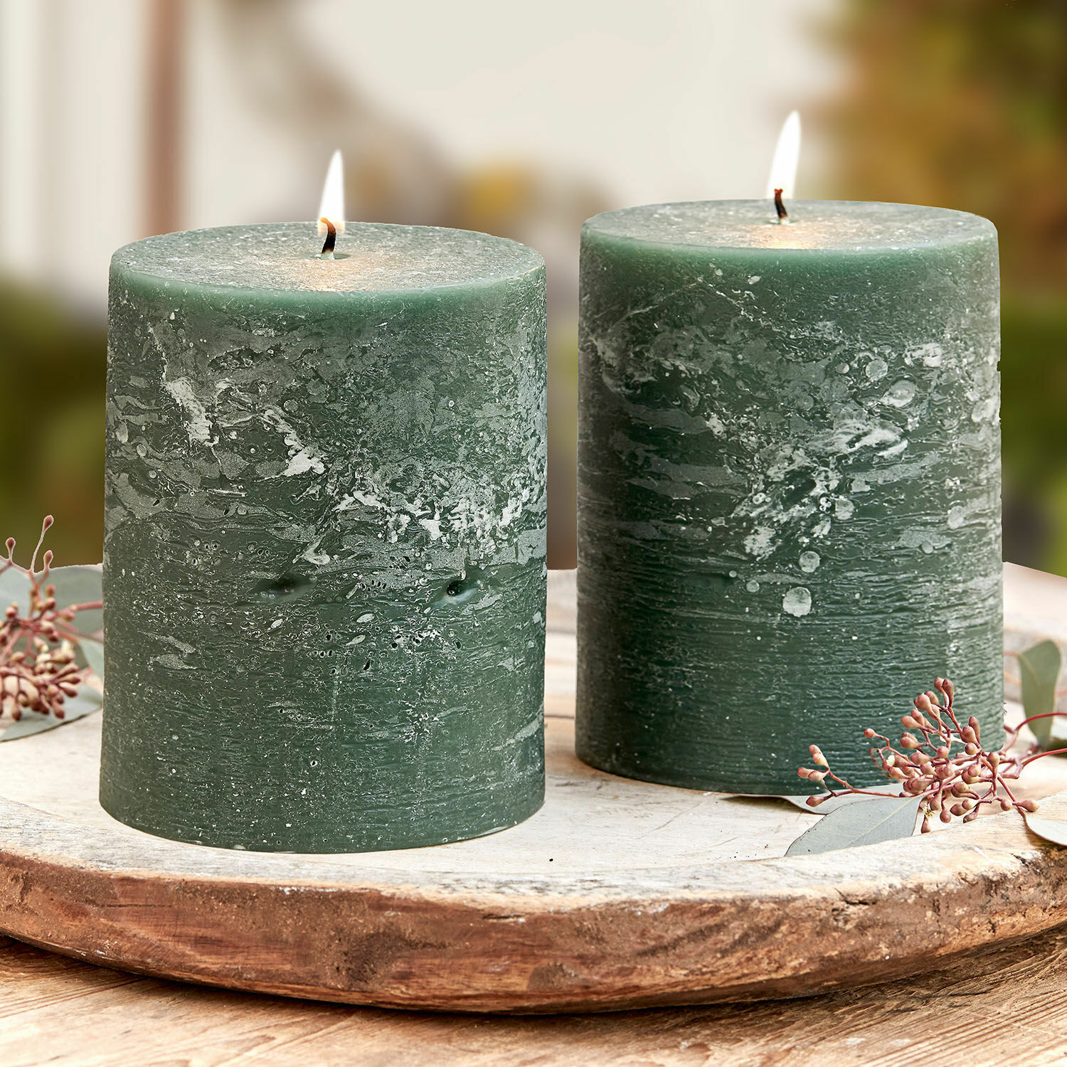 Lot de 2 bougies Oviedo Deux bougies vertes en cire avec texture rustique sur un plateau en bois, décoration intérieure.