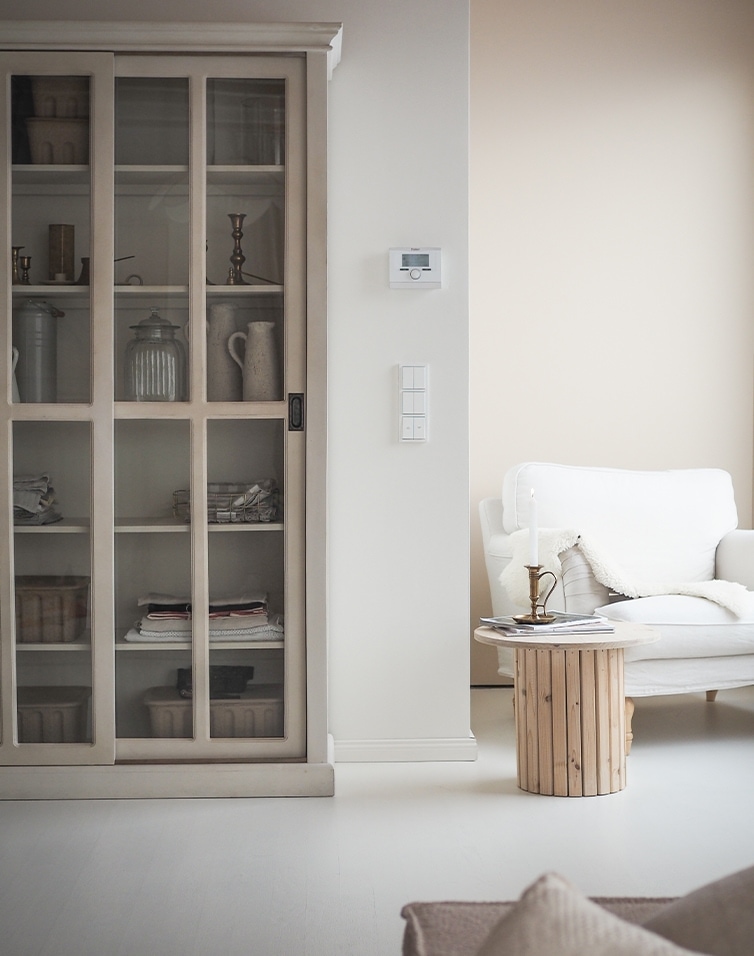 Salon lumineux avec canapé blanc, table basse en bois et armoire vitrée dans un style scandinave