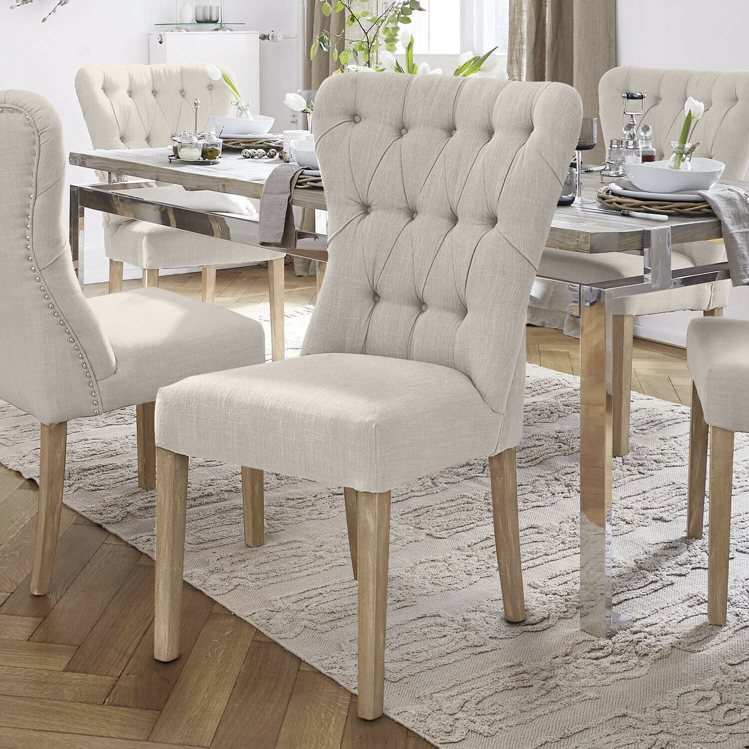 Chaises rembourrées beige avec pieds en bois autour d'une table en bois clair dans une salle à manger