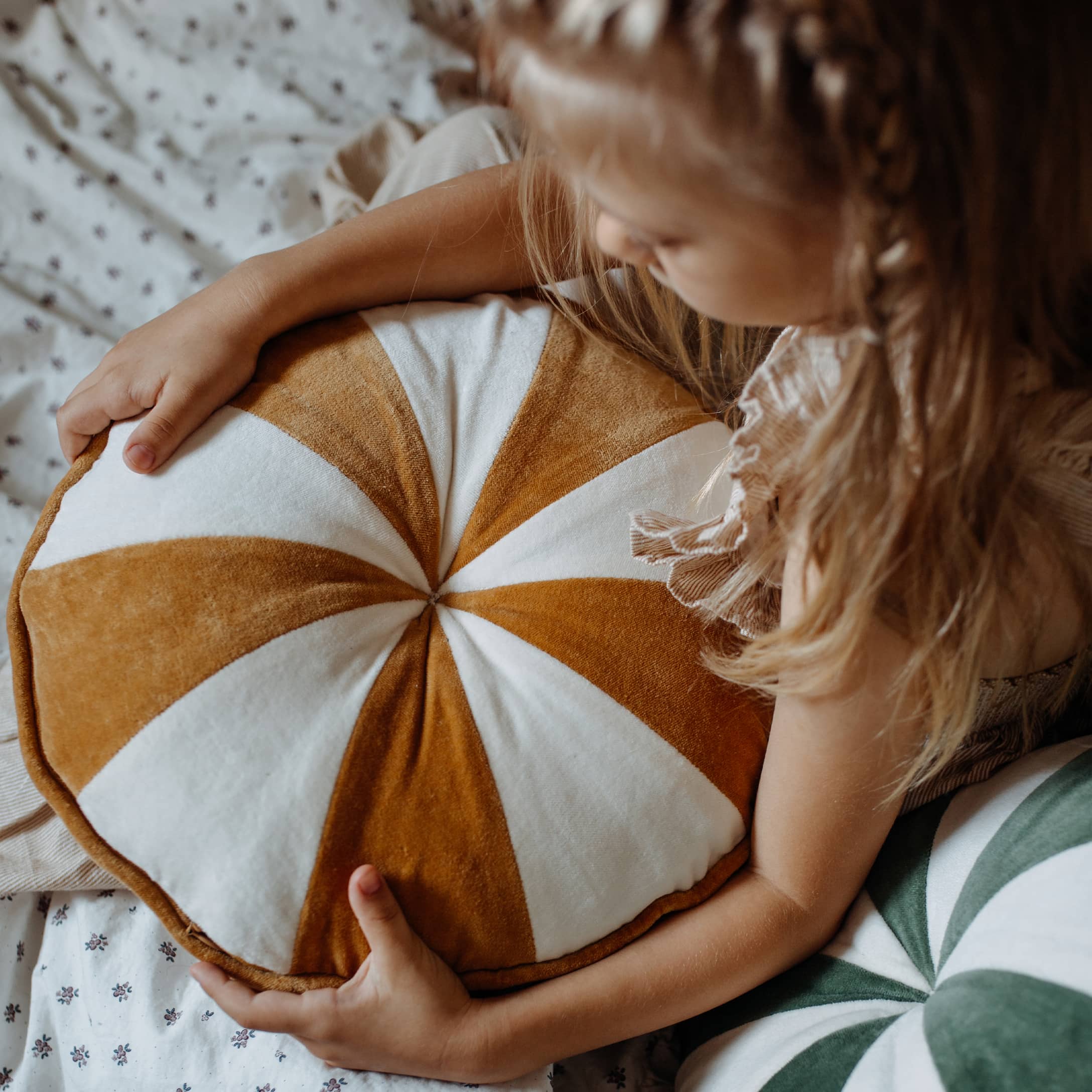 Enfant tenant un coussin rond en velours blanc et marron, décoration douce pour chambre d'enfant