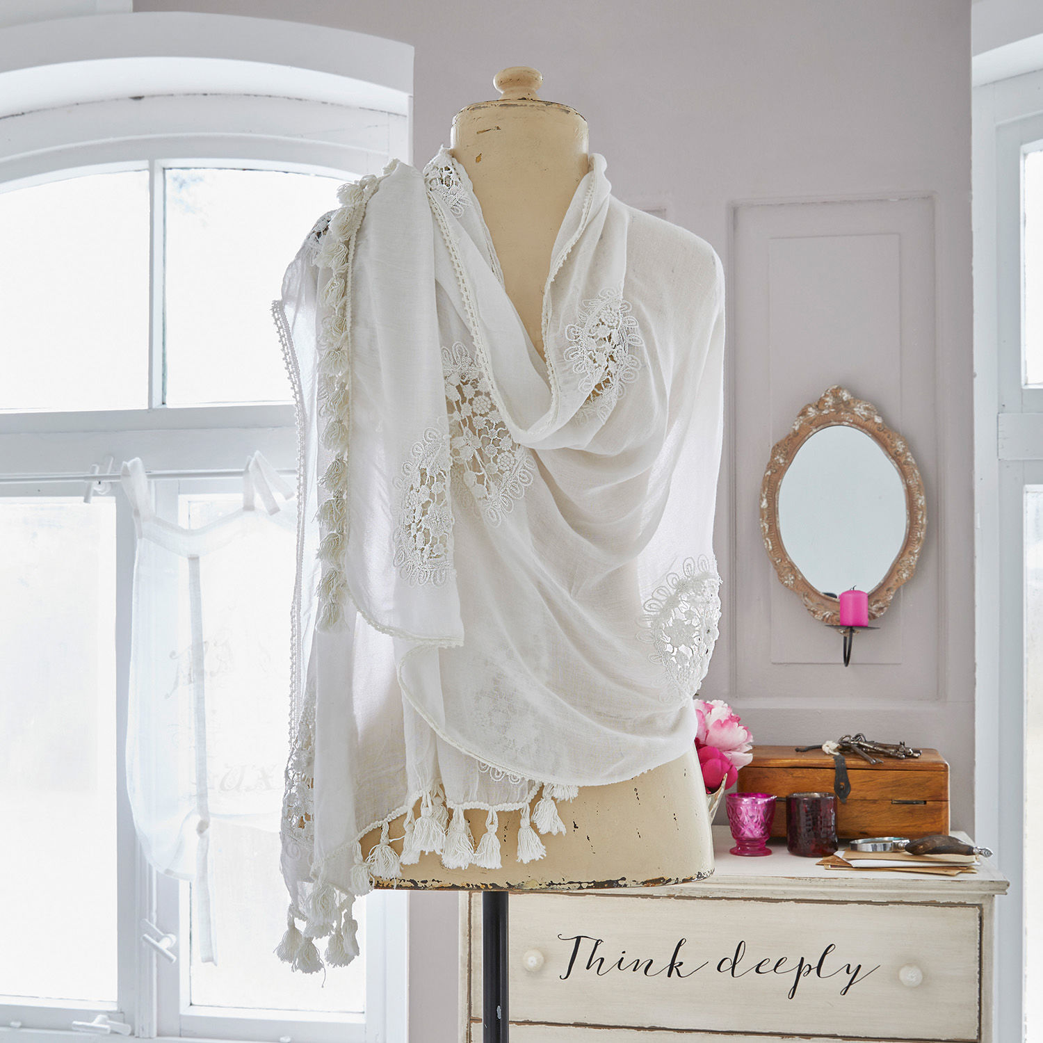 Étole Zelie Écharpe blanche en tissu léger avec dentelle et pompons sur mannequin dans une pièce lumineuse