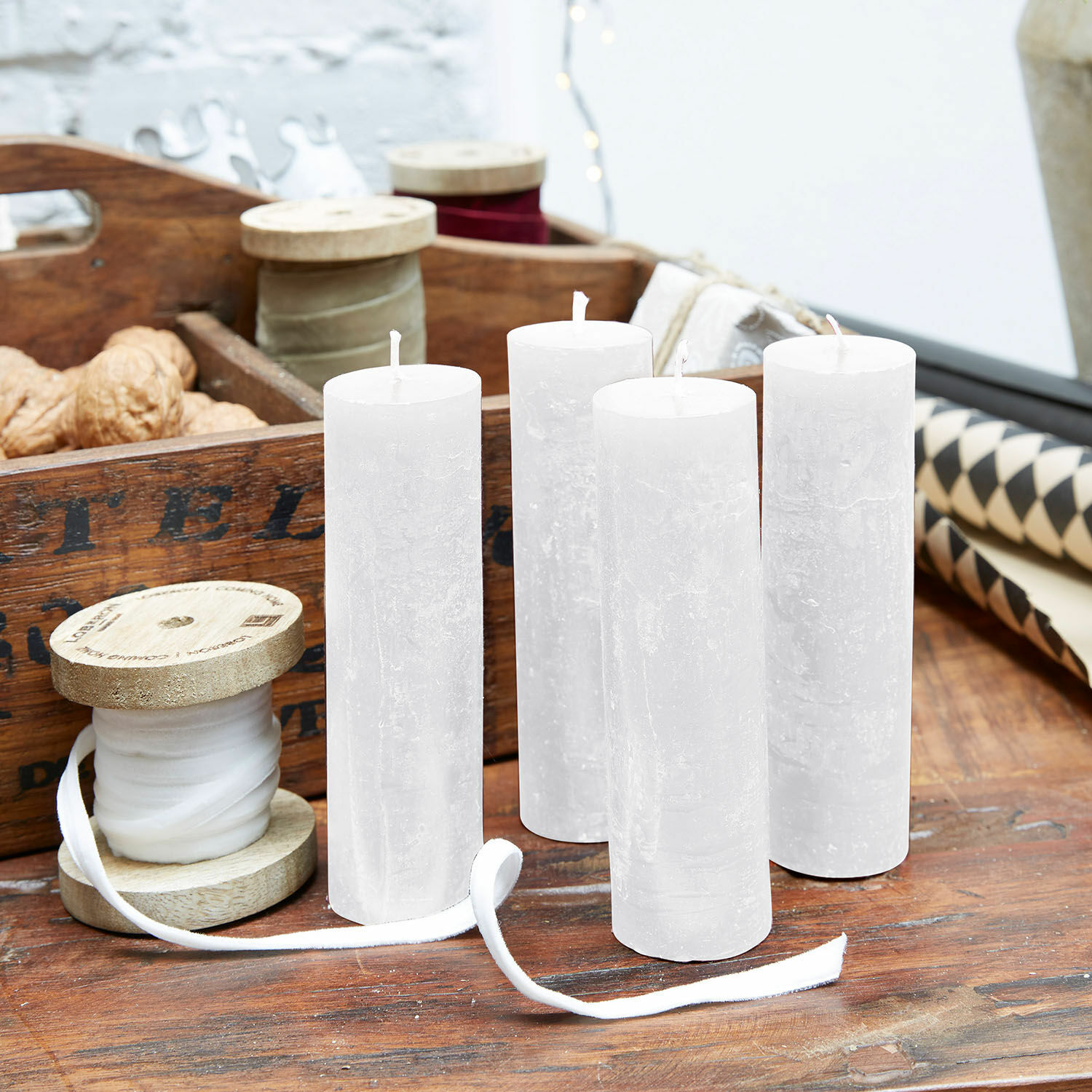 Lot de 4 bougies Muriel Ensemble de quatre bougies blanches en cire naturelle sur une table en bois avec décorations