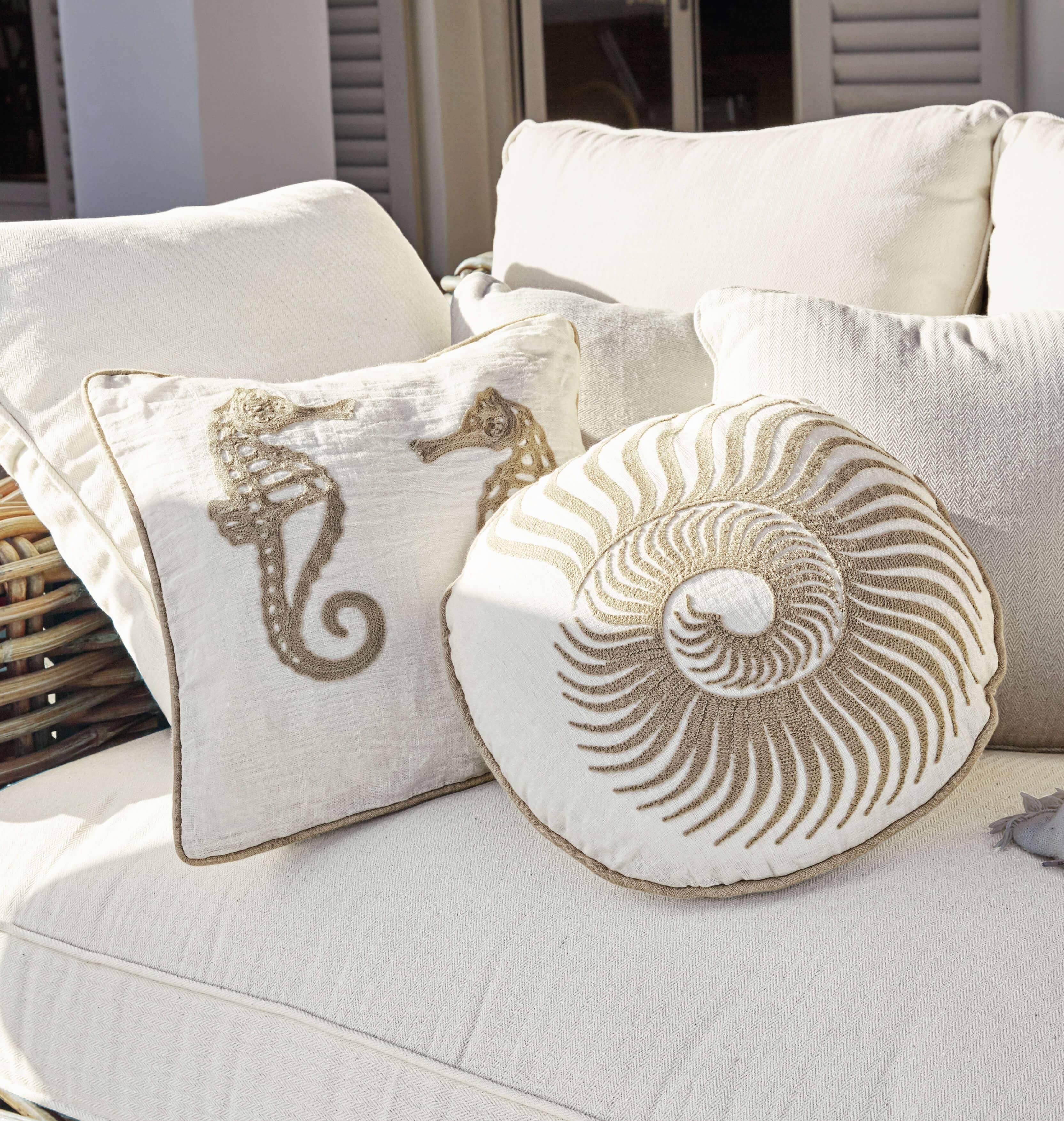 Coussins décoratifs beige avec motifs marins sur canapé clair, textiles d'intérieur