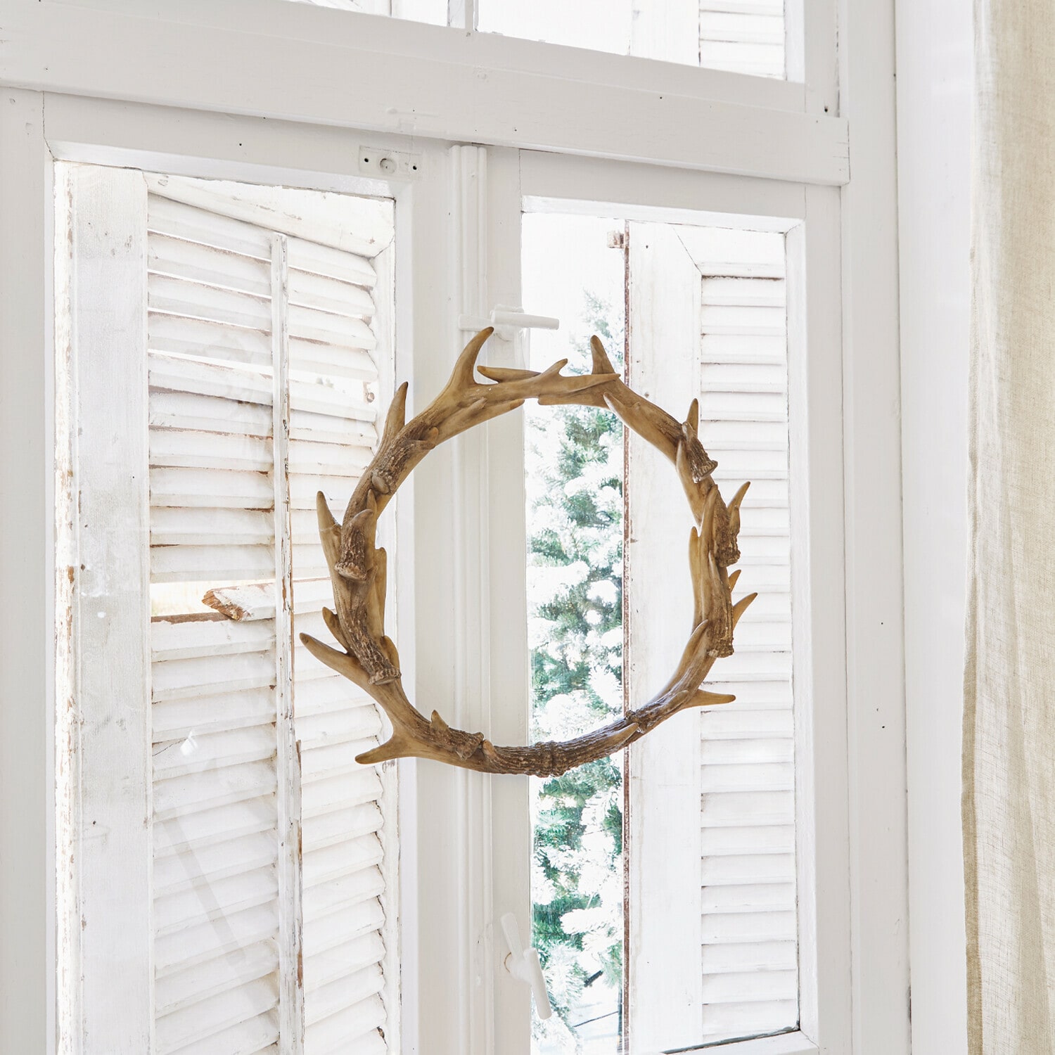 Couronne Marcelle Couronne décorative en bois en forme de bois de cerf sur fenêtre blanche avec bougies et pommes de pin