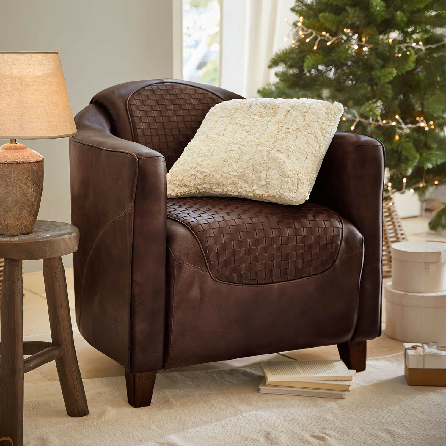 Fauteuil Westerdales Fauteuil en cuir marron tressé avec coussin crème, ambiance chaleureuse avec lampe et sapin décoré