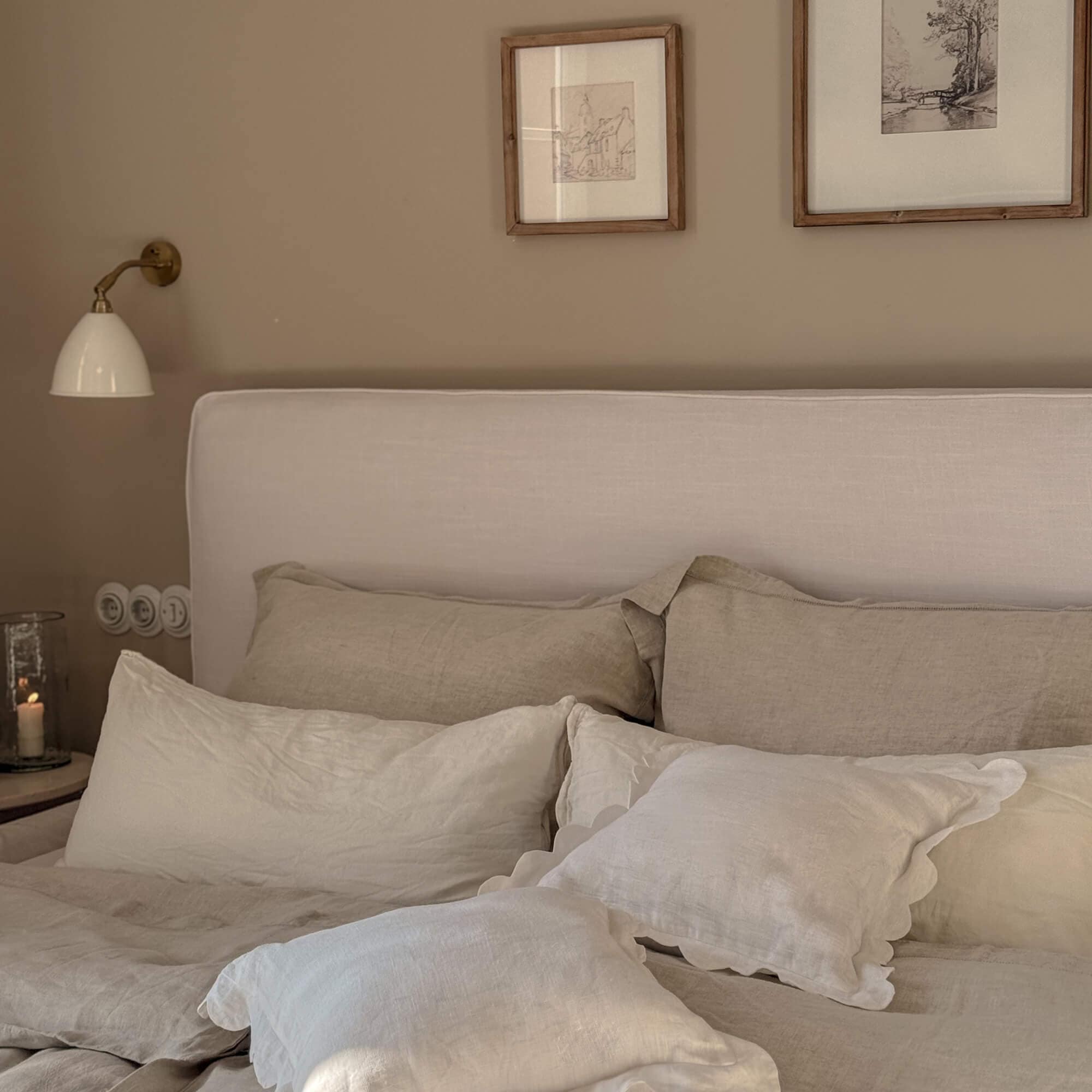 Oreillers en lin beige et blanc sur un lit avec une tête de lit claire dans une chambre cosy