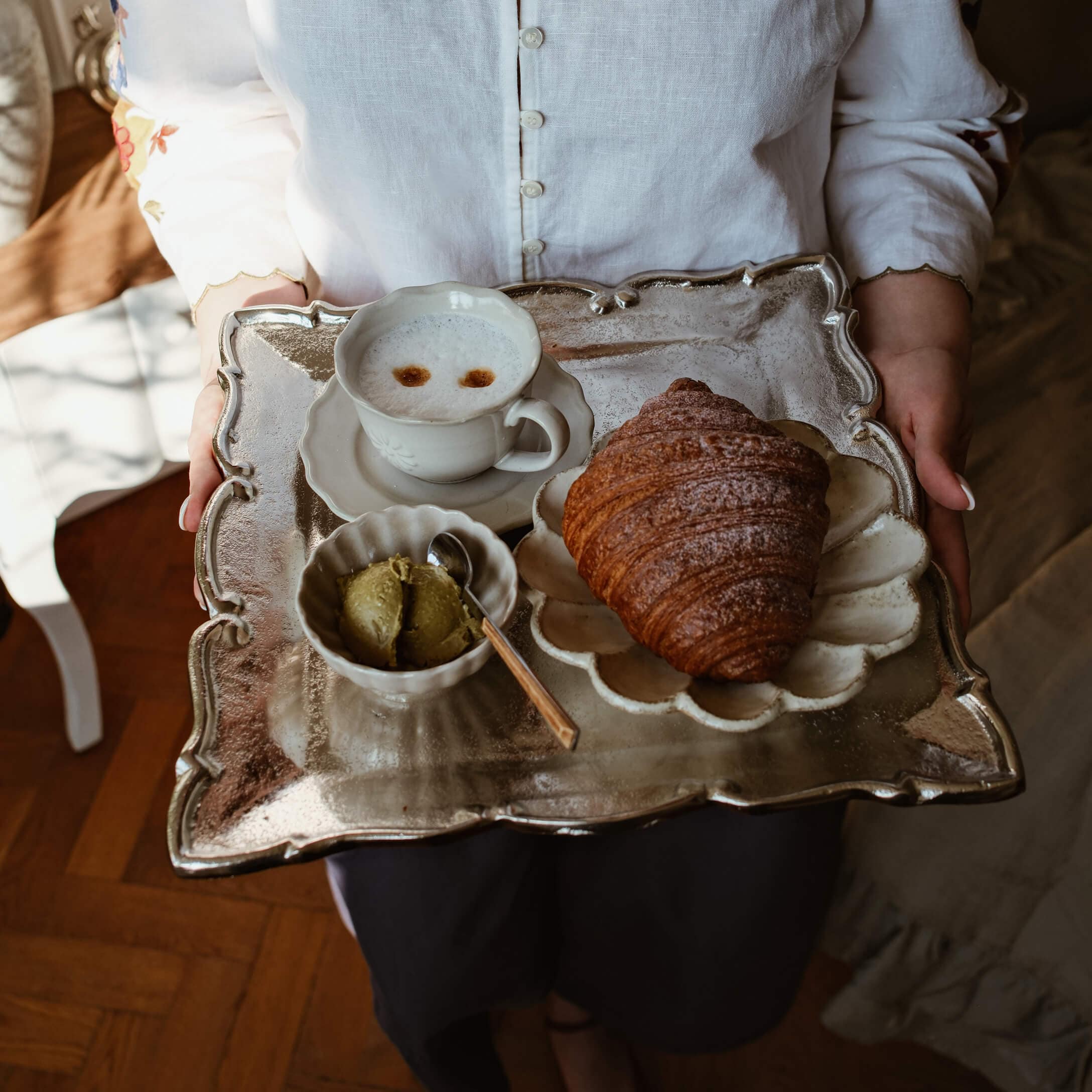 Plateau en métal avec croissant, tasse de café et beurre vert sur porcelaine blanche élégante