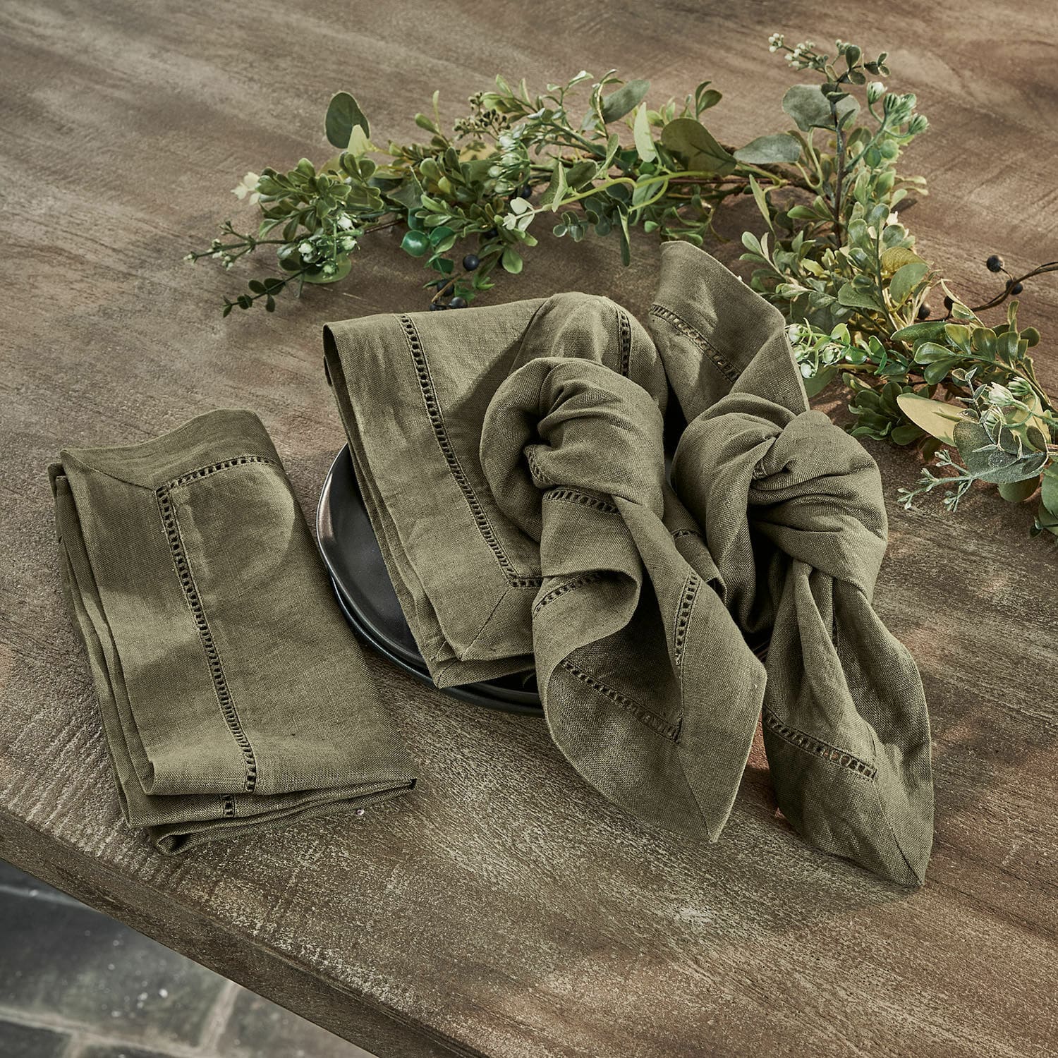 Lot de 4 serviettes Covent Garden Ensemble de serviettes en lin vert avec couture décorative sur table en bois avec décoration végétale