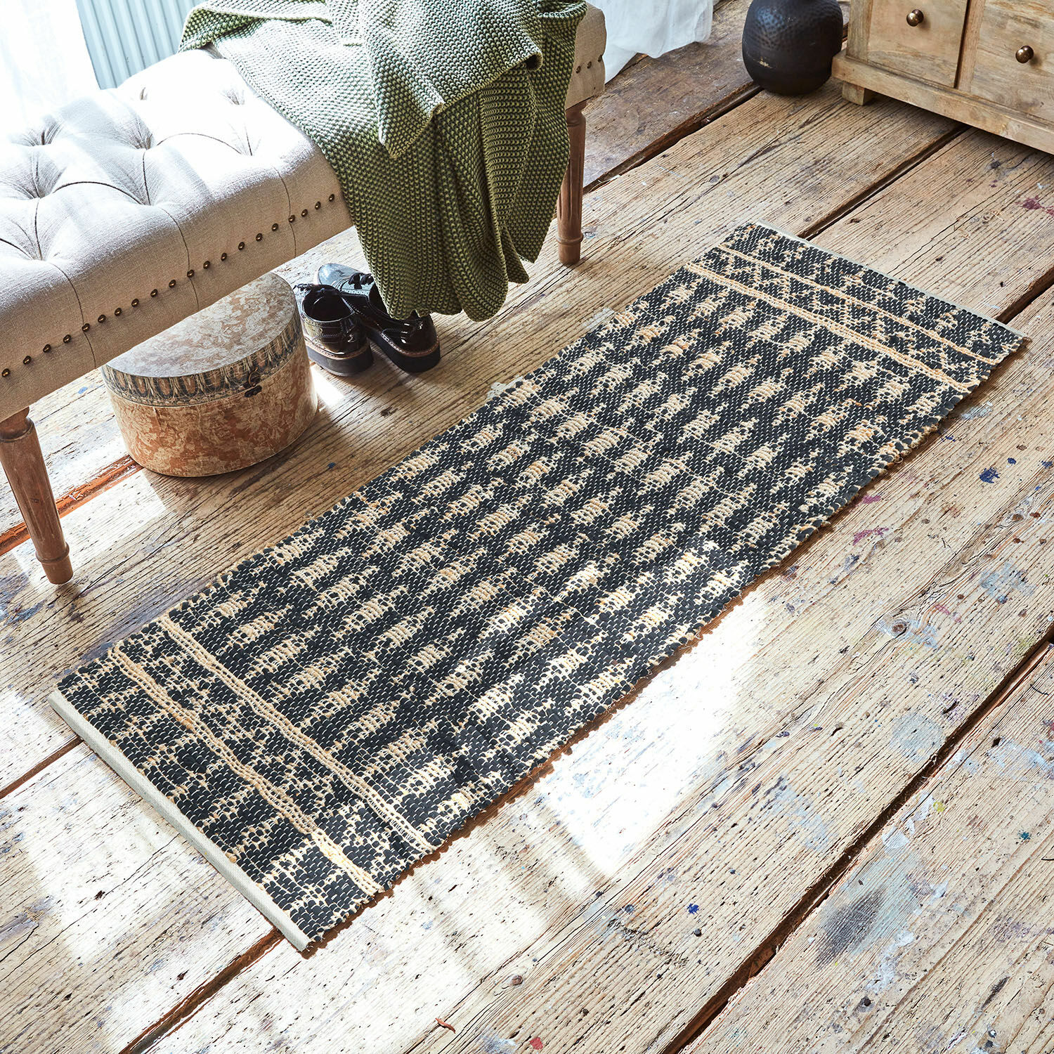 Tapis long Frizzy Tapis noir et beige en matériau naturel sur un sol en bois dans un intérieur élégant