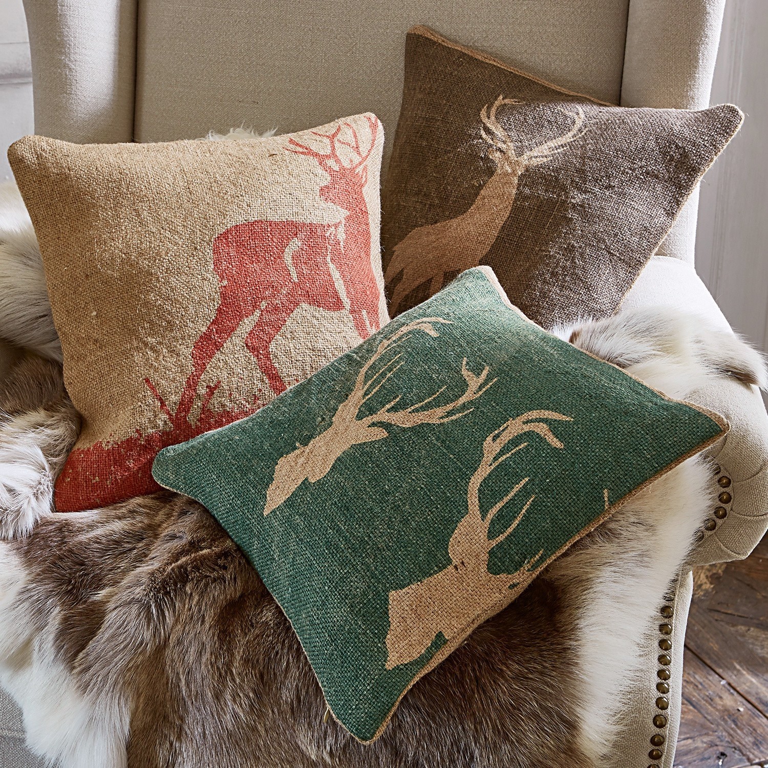 Lot de 3 housses de coussins Shrewton Trois coussins décoratifs avec motif de cerf en couleurs naturelles sur fauteuil avec couverture en fourrure