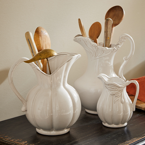 Ensemble de trois pichets en céramique blanche ornée, remplis de cuillères en bois pour cuisine rustique