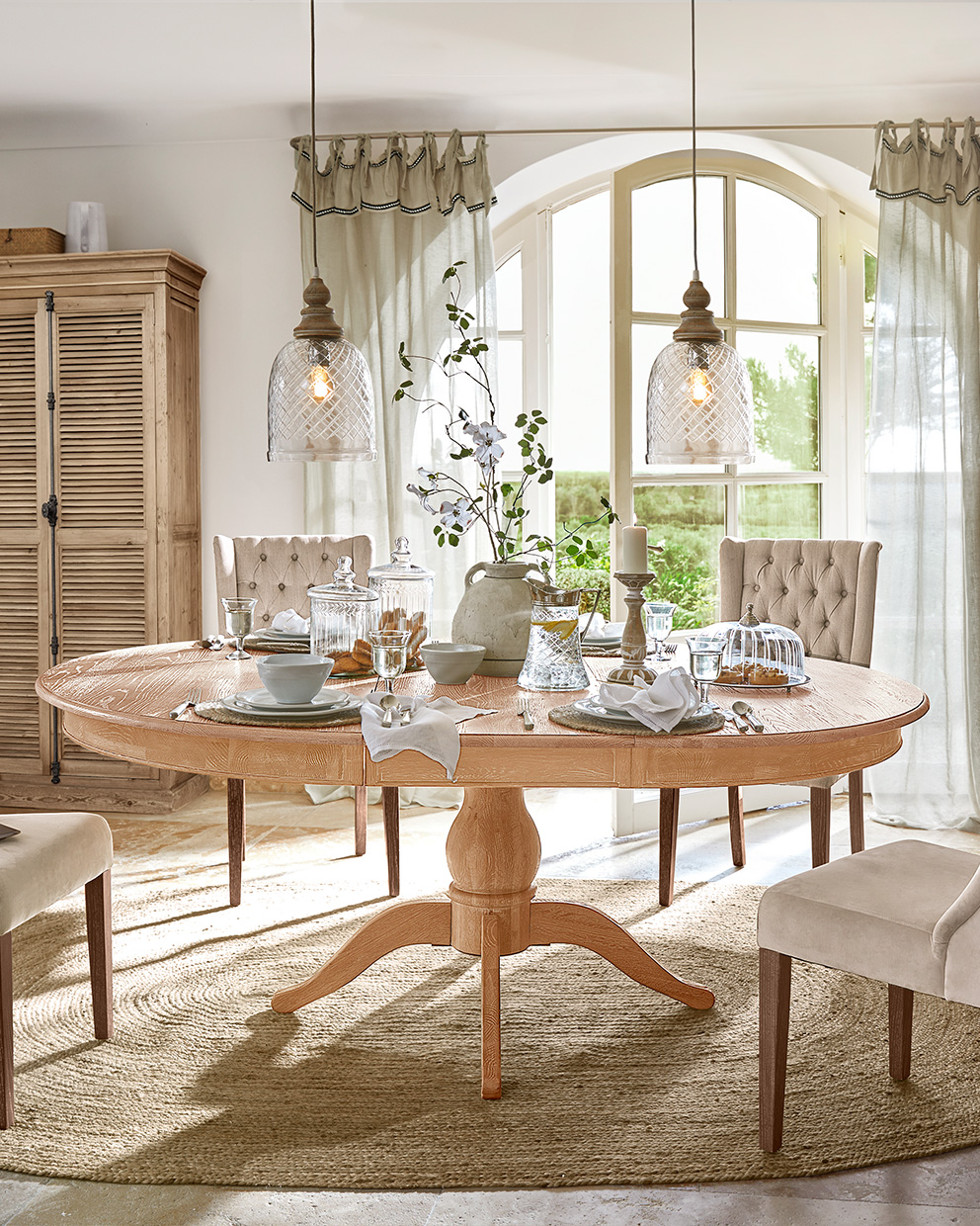 Table à manger ovale en bois naturel avec chaises beige et décorations de table lumineuses