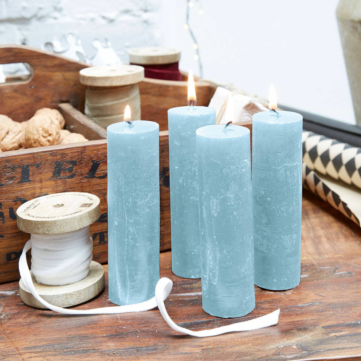 Lot de 4 bougies Muriel Ensemble de quatre bougies bleues en cire naturelle sur une table en bois avec décorations