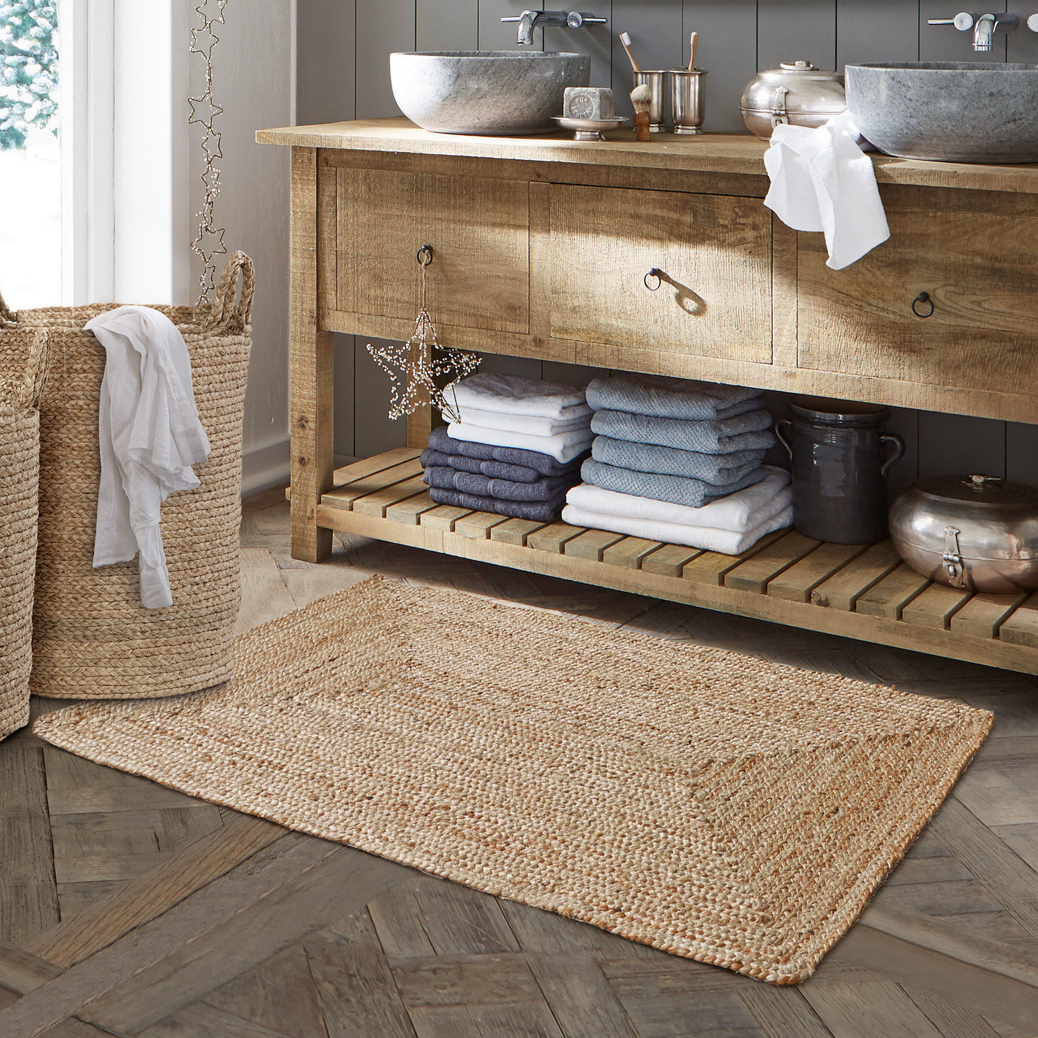 Tapis de bain Busselton Tapis de salle de bain en jute naturelle beige posé sur un sol en bois avec panier à linge tressé