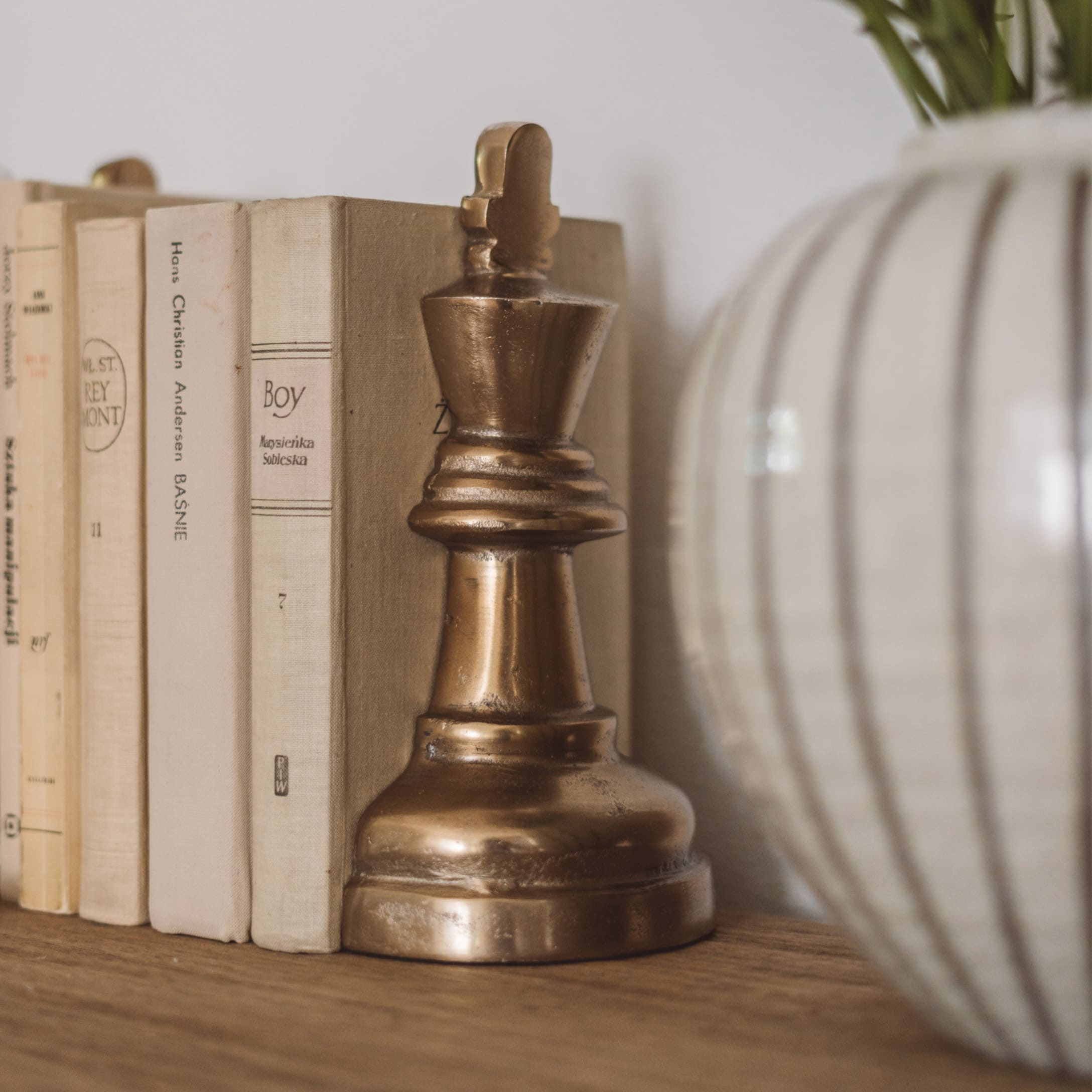 Soutien-livres décoratif en métal couleur laiton en forme de pièce d'échecs sur étagère en bois