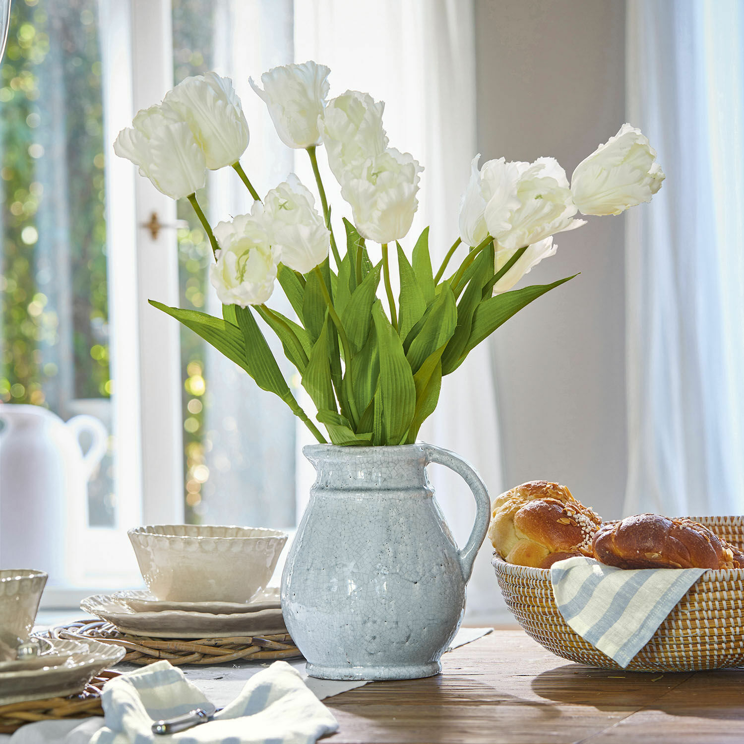 Lot de 6 fleurs décoratives Lamarr Pichet en céramique blanche avec bouquet de tulipes blanches sur table en bois avec pain et vaisselle