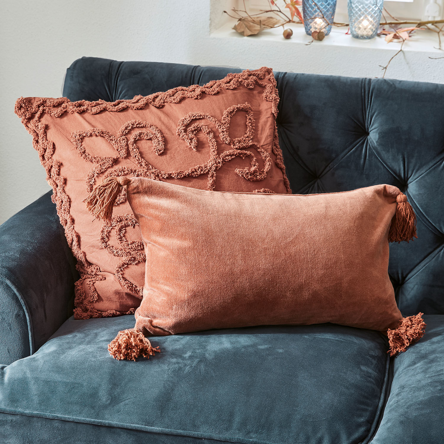 Lot de 2 housses de coussins Posadas Deux coussins décoratifs en velours orange sur un canapé bleu marine, accessoires doux et élégants pour salon