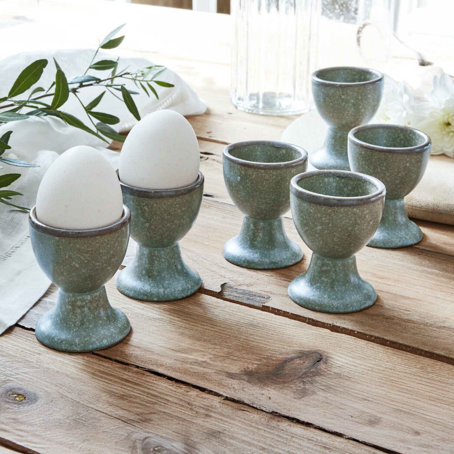 Lot de 6 coquetiers Biarré Ensemble de six coquetiers en céramique verte posés sur une table en bois pour la cuisine