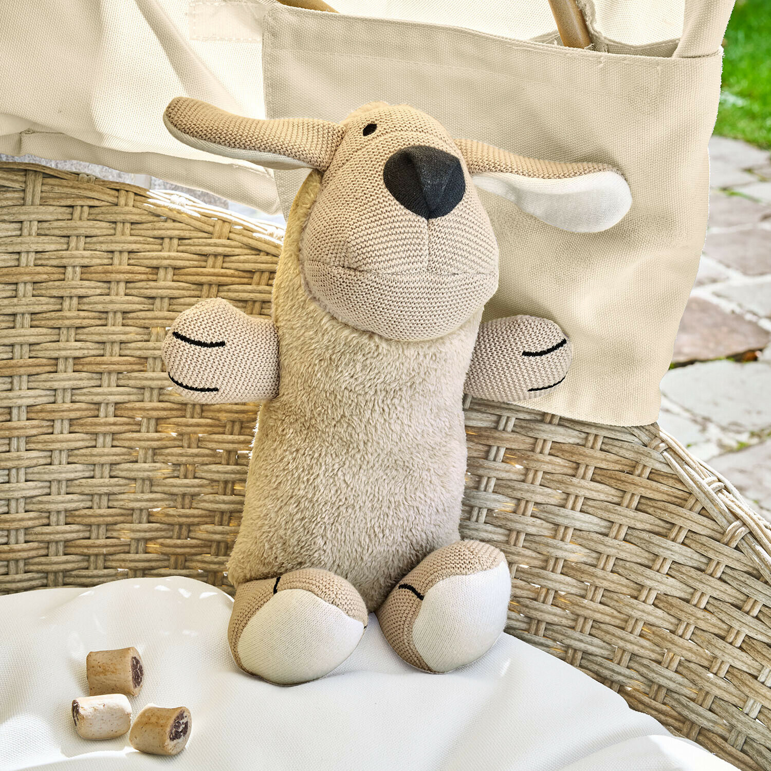 Peluche mouton beige avec corps en peluche douce et détails en tricot sur une chaise en rotin