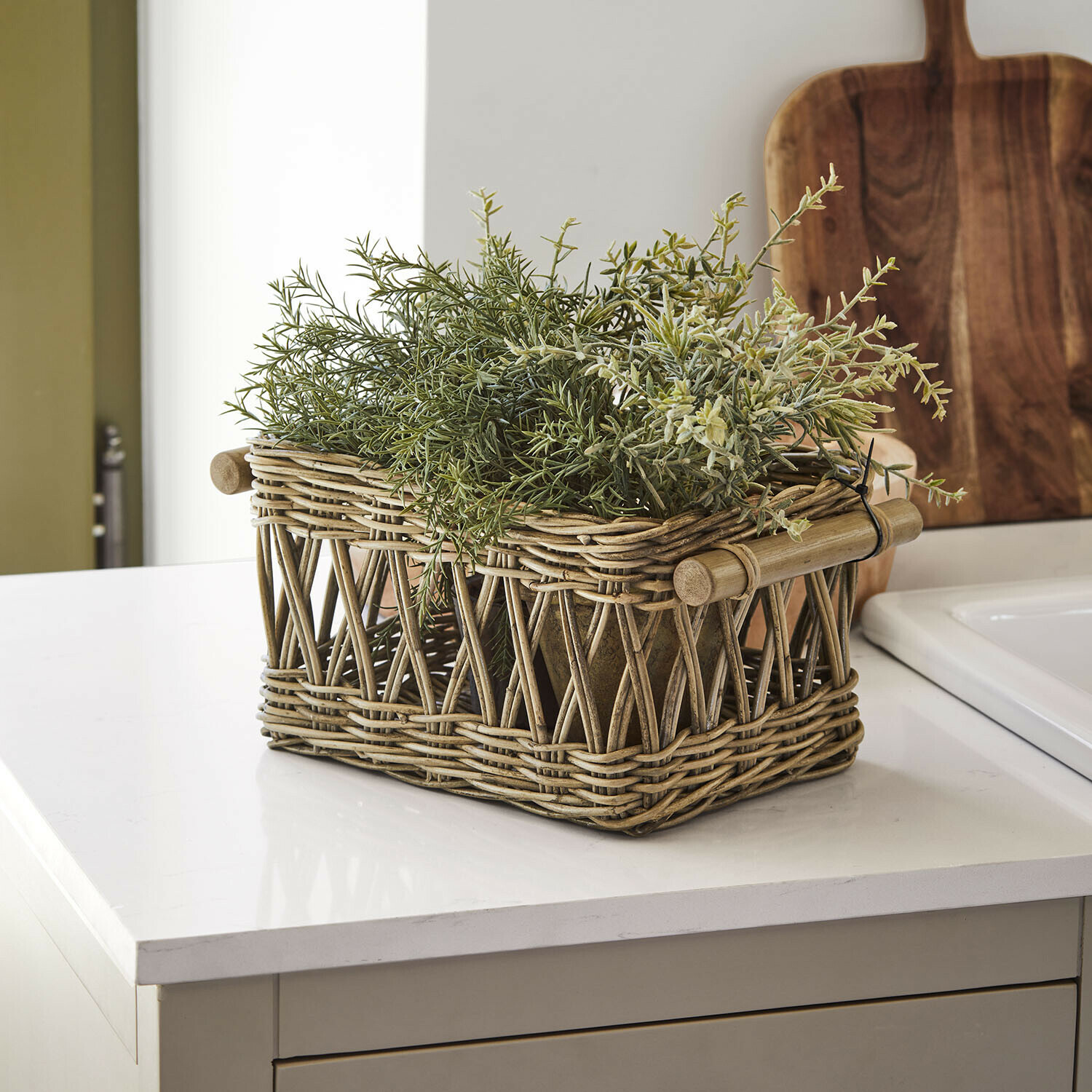 Panier Kettlewells Panier en rotin naturel avec plantes vertes posé sur un plan de travail de cuisine moderne