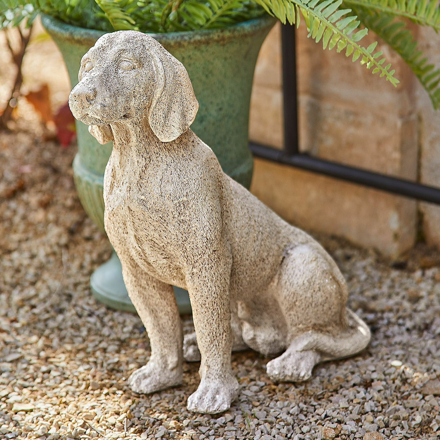 Chien décoratif Albinor Statue décorative de chien en pierre beige posée dans un jardin extérieur