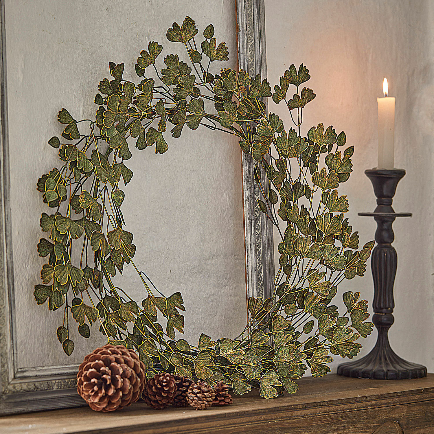 Couronne Syrdarja Couronne décorative en feuilles vertes posée sur une étagère en bois avec pommes de pin et bougie