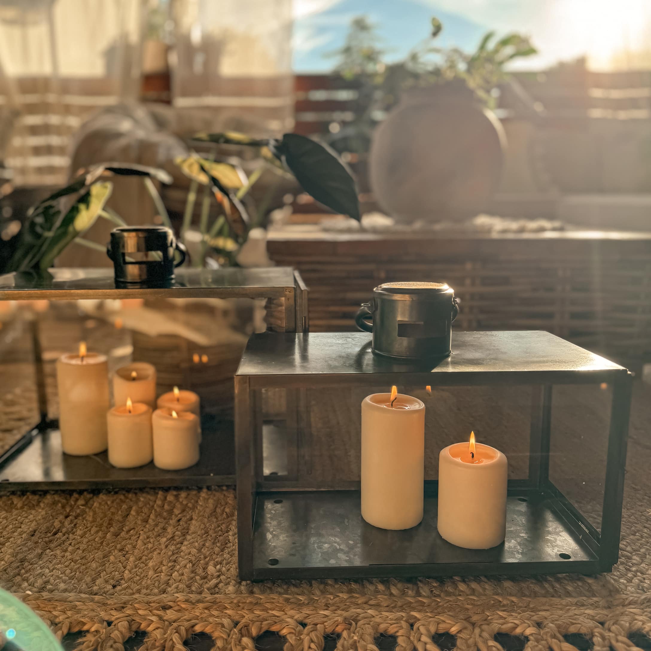 Bougeoirs en métal avec bougies crème allumées sur tapis tressé dans un intérieur chaleureux