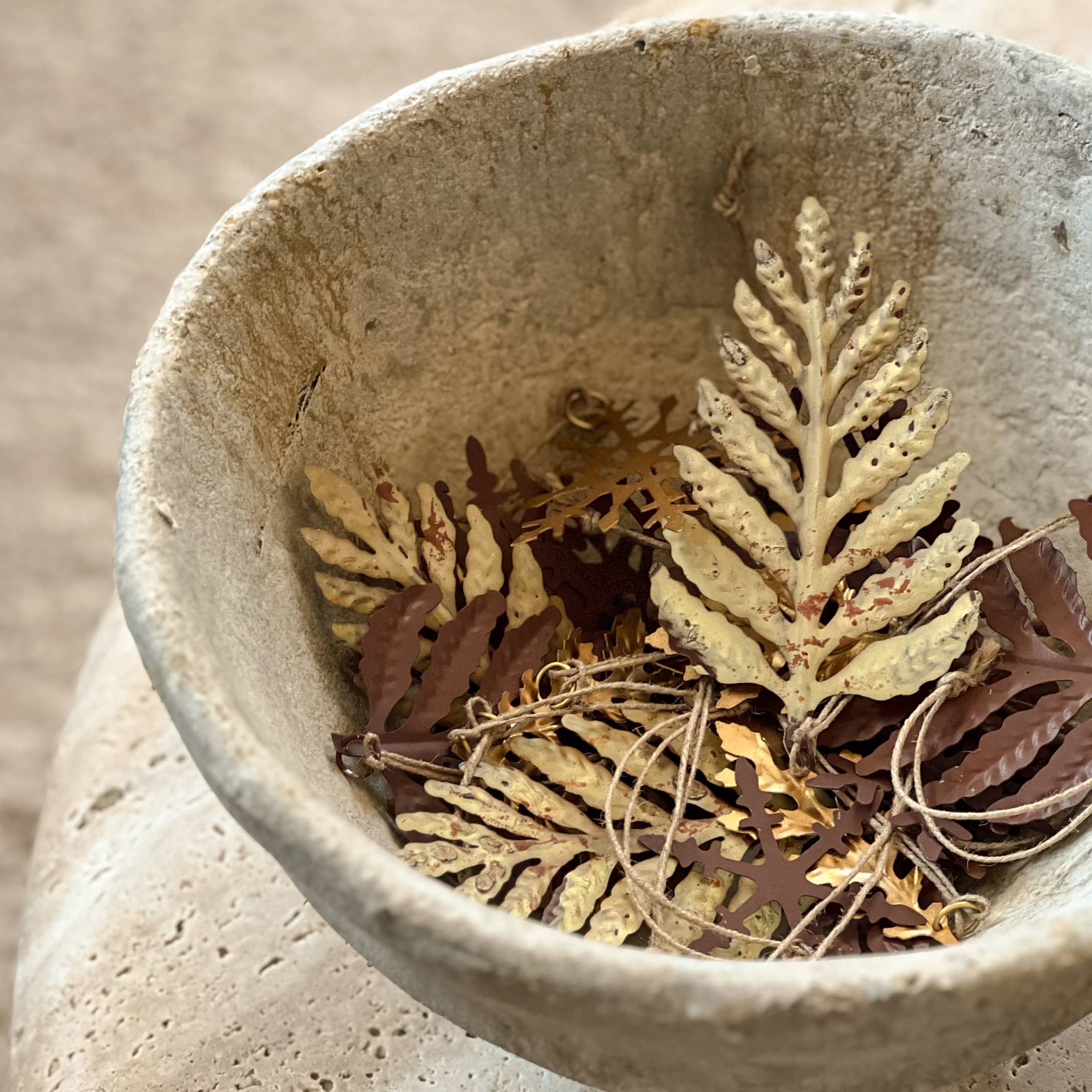 Feuilles décoratives en métal beige dans un bol en pierre, décoration intérieure et saisonnière