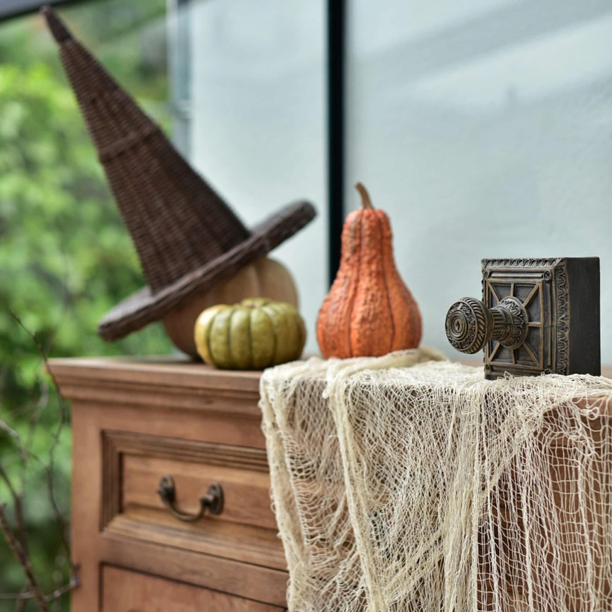 Commode en bois décorée avec chapeau de sorcière en osier et citrouilles pour Halloween