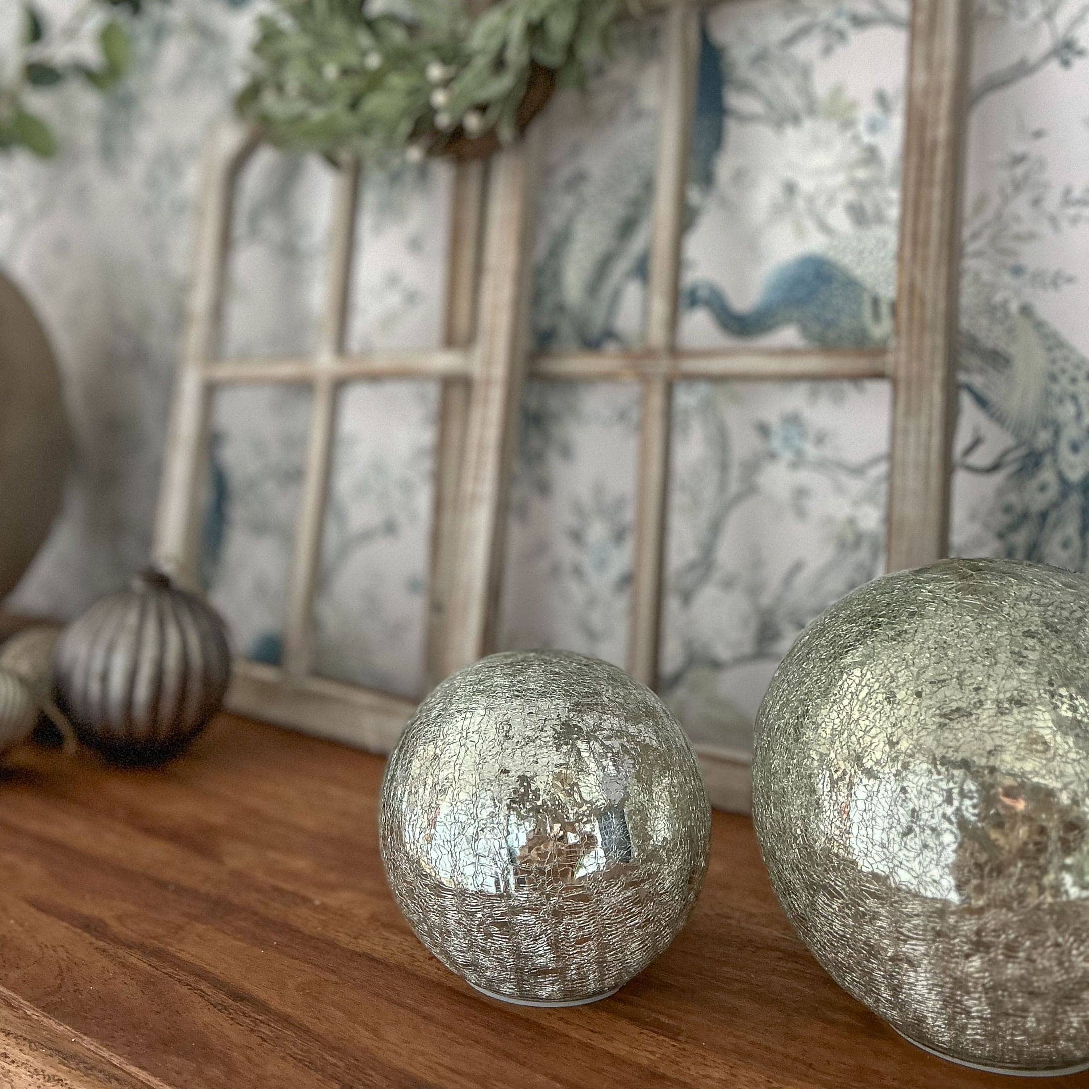 Boules décoratives argentées à surface craquelée posées sur une table en bois pour décoration intérieure