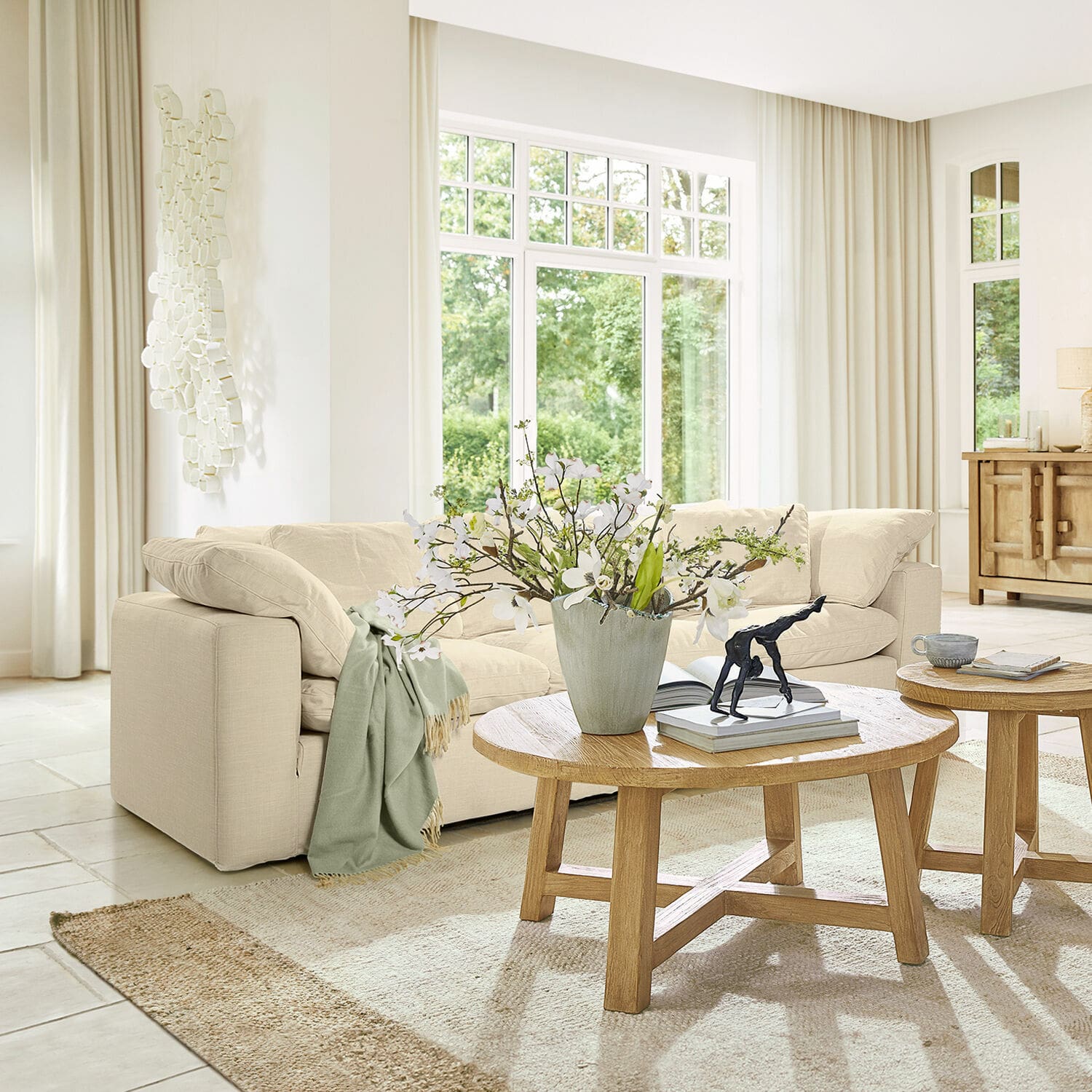 Canapé Queensbridge Canapé beige clair en tissu dans un salon moderne avec table basse en bois et décoration florale