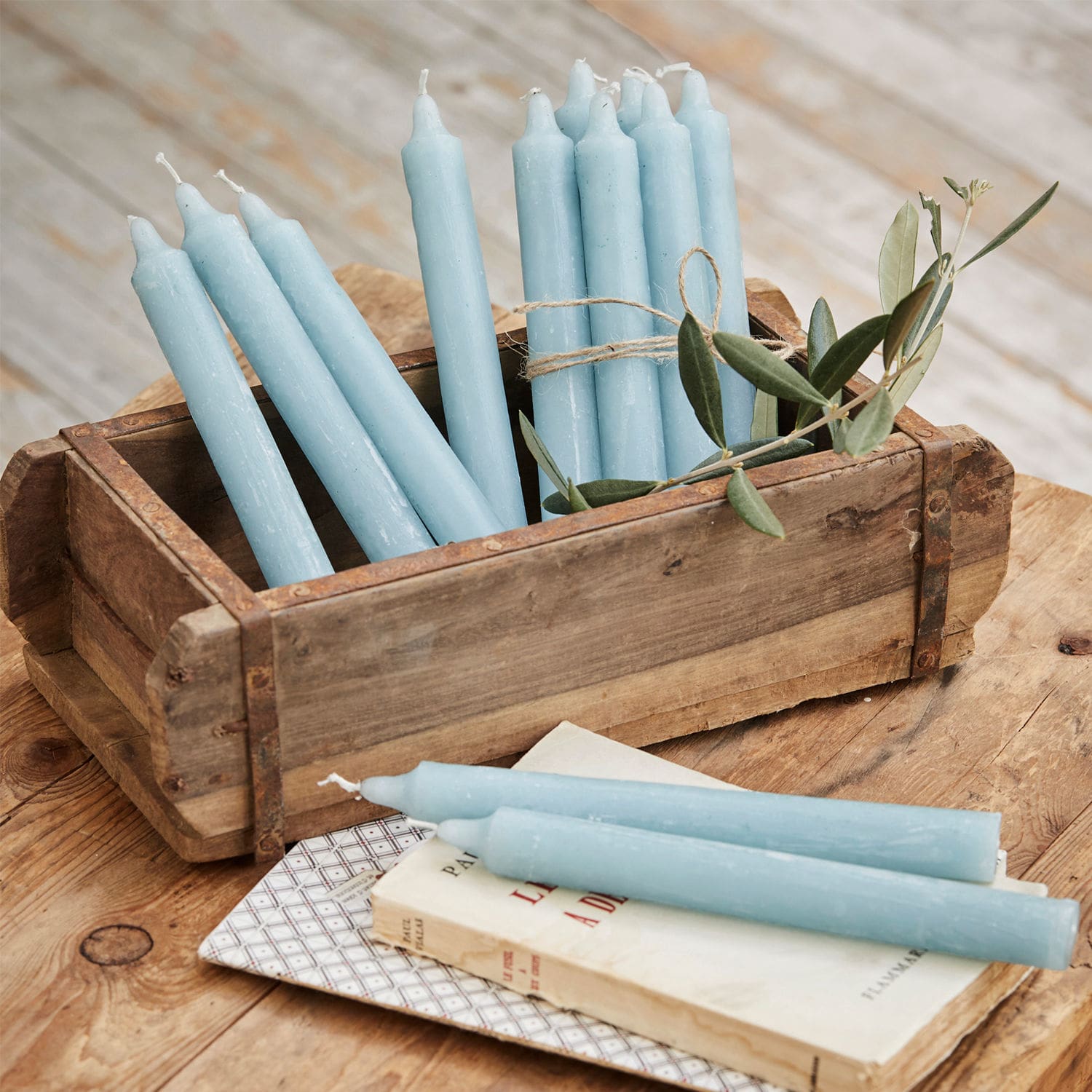 Lot de 12 bougies Bauceau Lot de bougies bleues en cire dans une caisse en bois sur une table rustique en bois