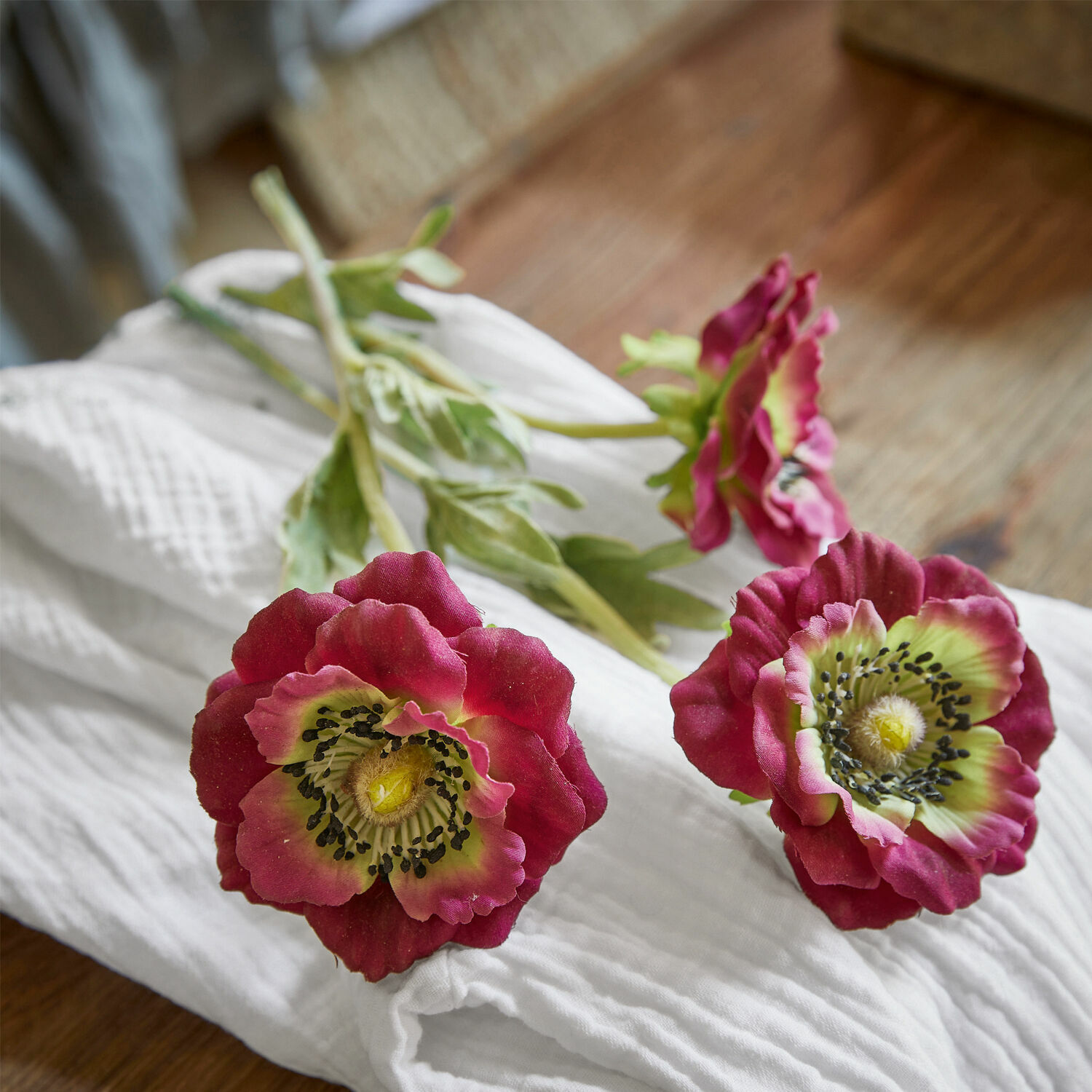 Lot de 3 fleurs décoratives Inara Fleurs artificielles de pavot bordeaux avec centre vert posées sur un tissu blanc, décoration intérieure