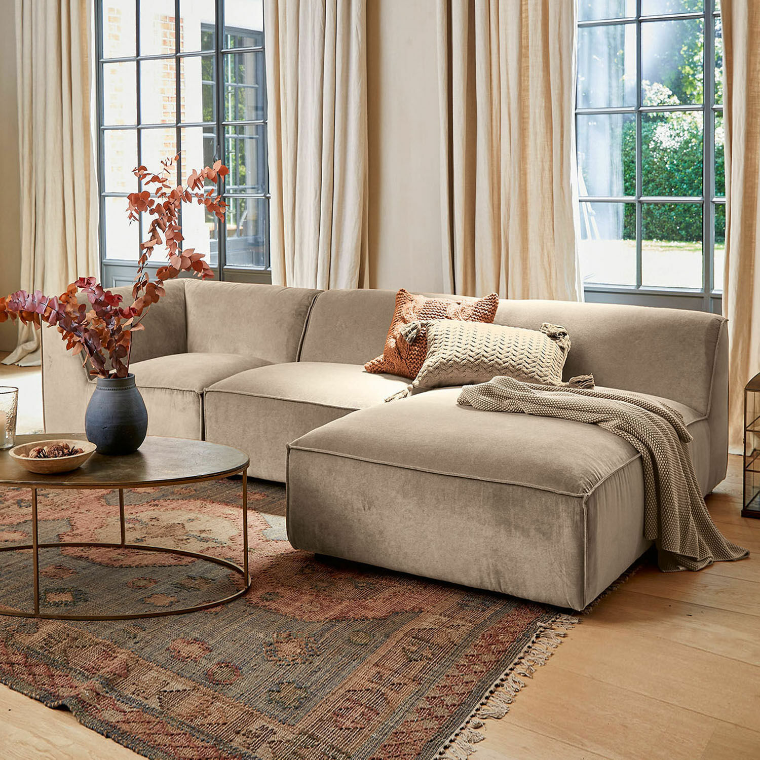 Canapé McLean Canapé d'angle beige en tissu doux dans un salon élégant avec tapis et table basse ronde