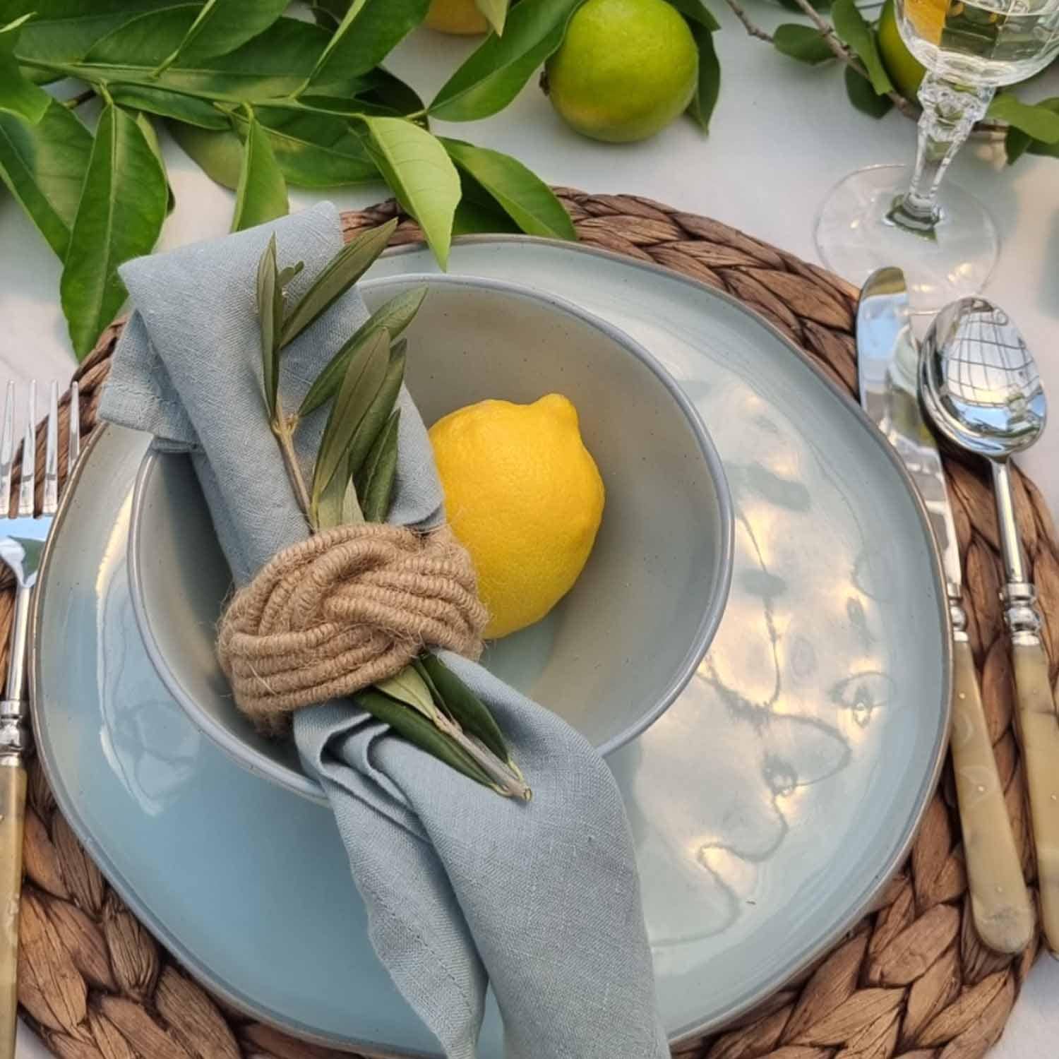 Service de table en céramique bleue avec serviette en lin et citron sur dessous de plat en osier