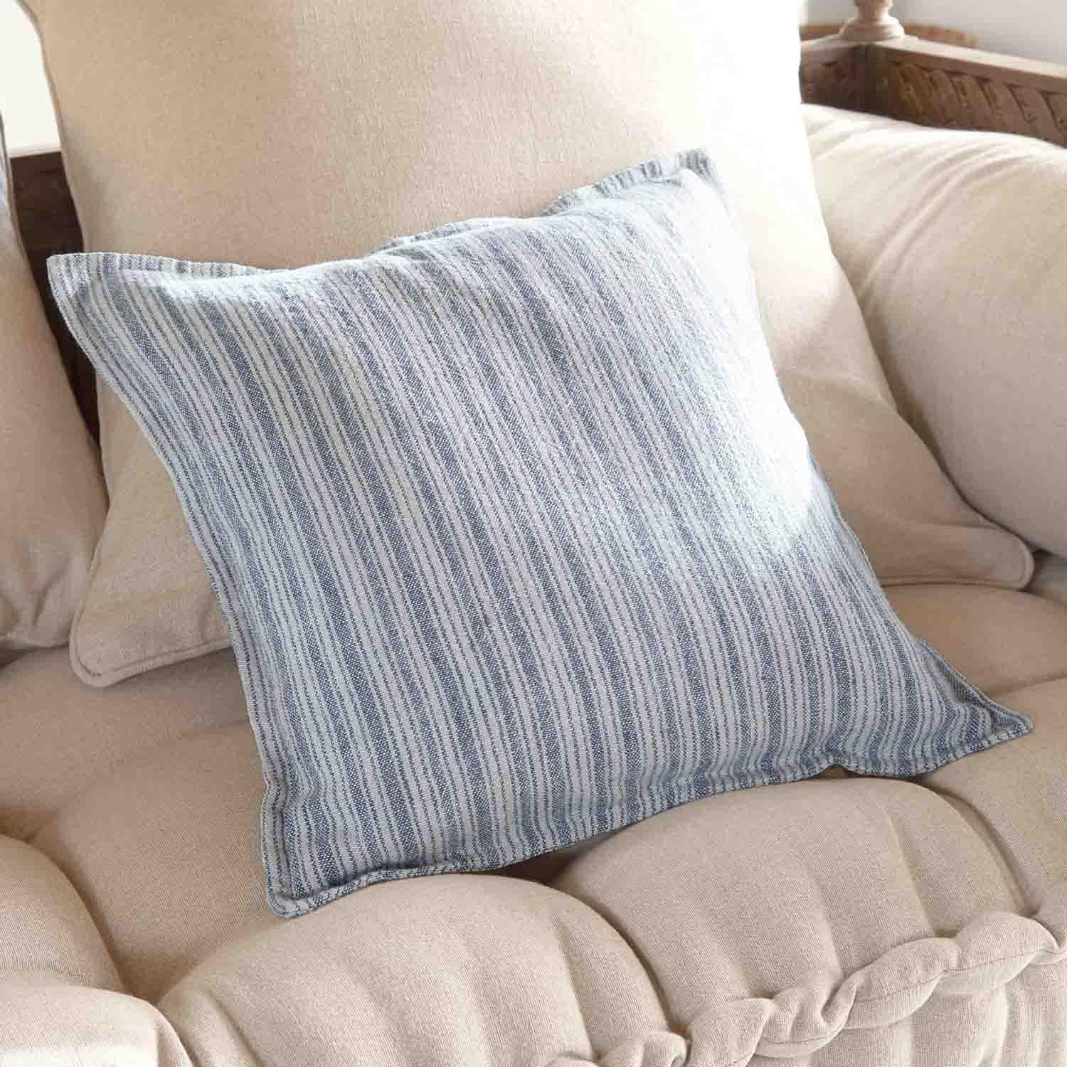 Coussin décoratif rayé bleu et blanc sur canapé beige, tissu doux, ambiance cosy maison