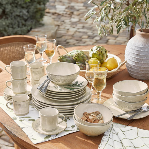 Service de vaisselle en céramique crème avec motif de feuilles vertes sur table en bois en extérieur