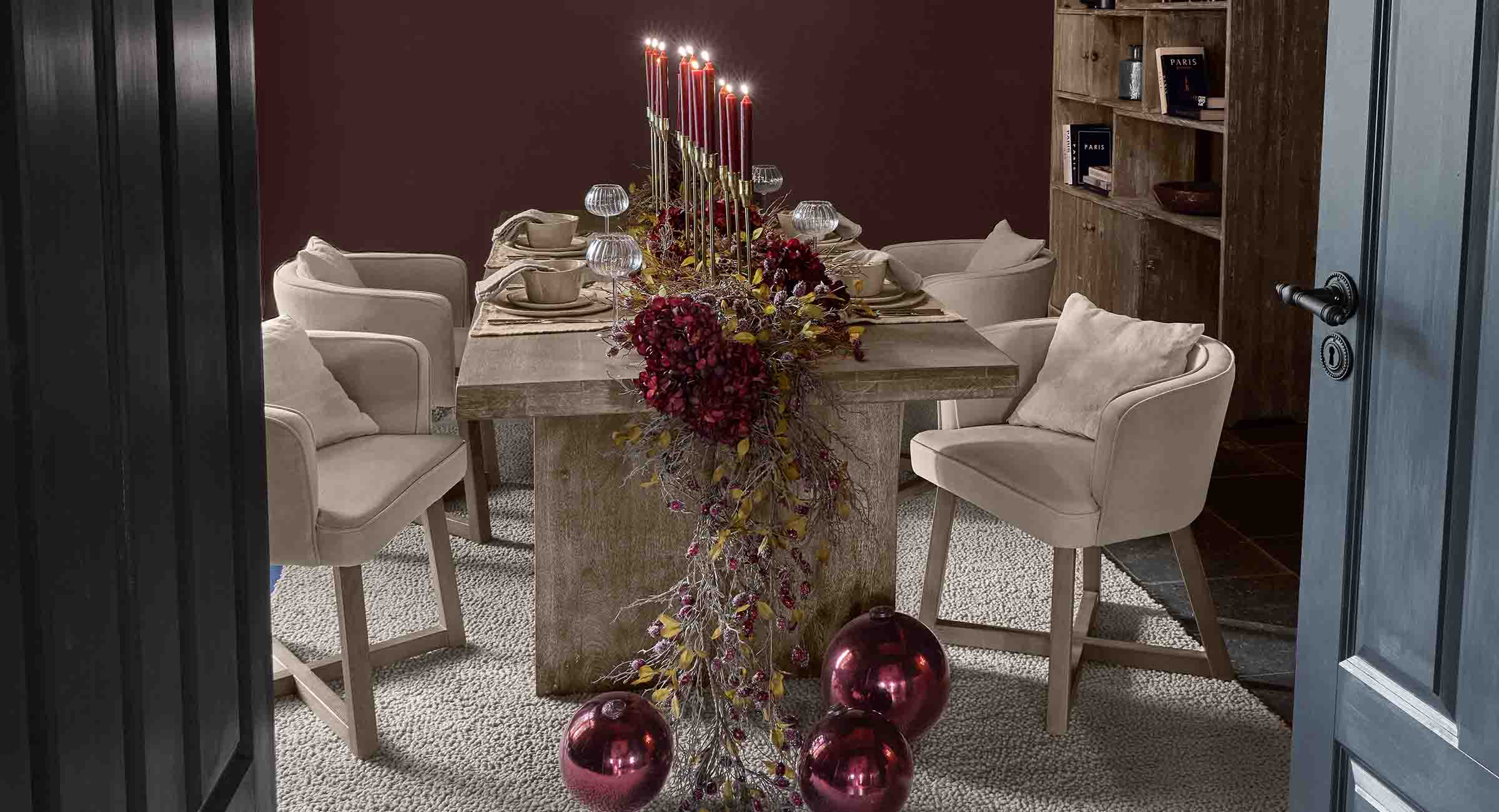 Table à manger élégante avec chaises beige et décoration festive rouge avec bougies allumées