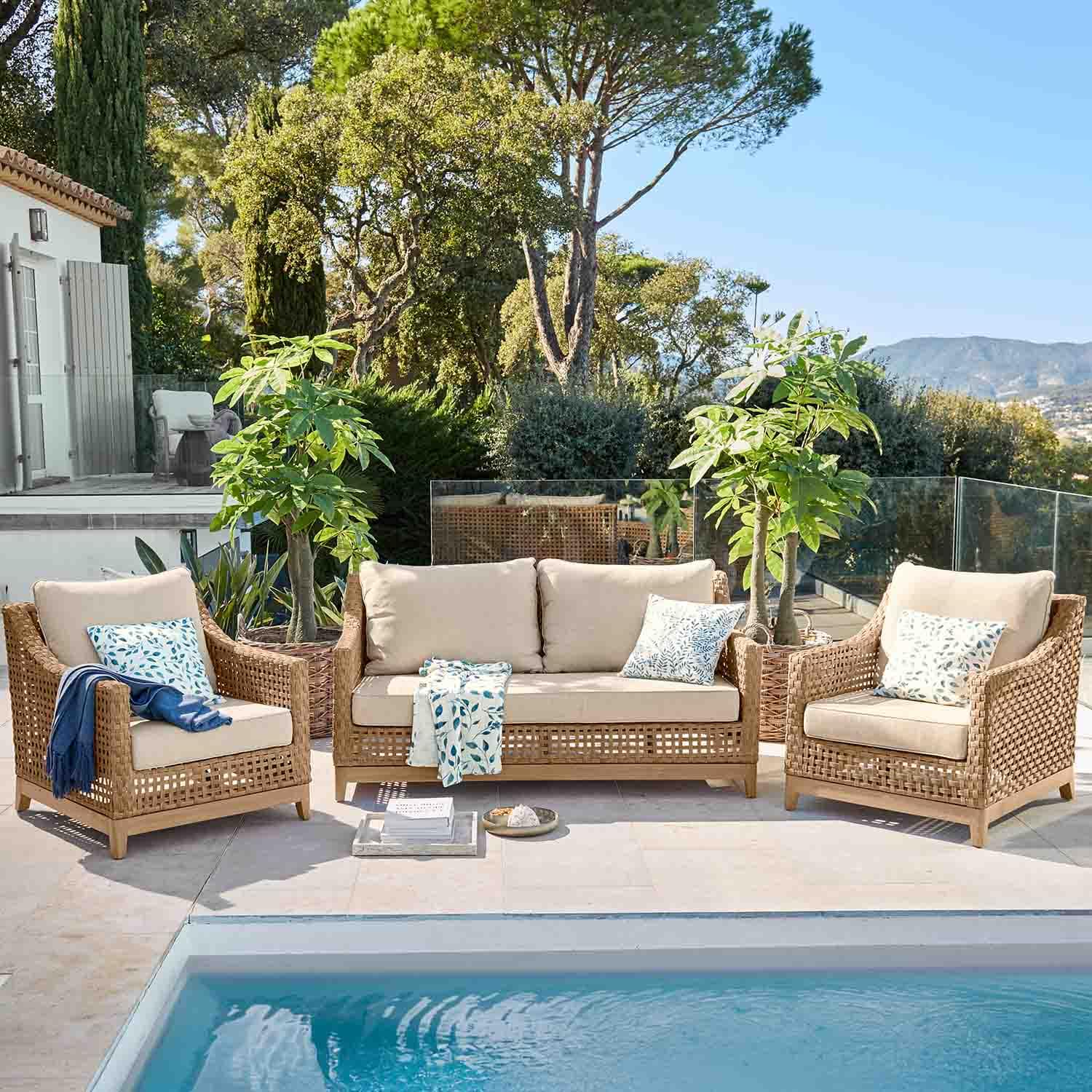 Ensemble de mobilier de jardin en rotin naturel avec coussins beige au bord de la piscine