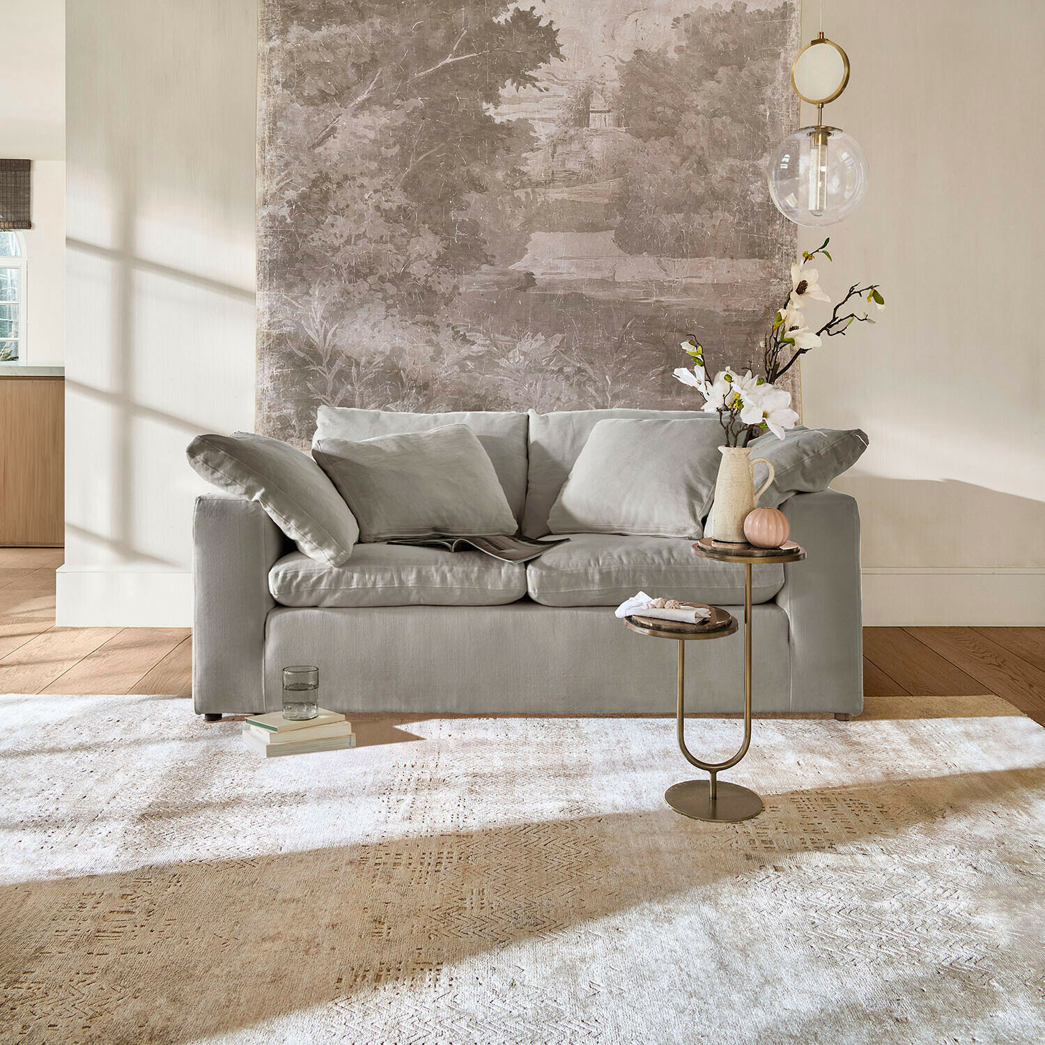 Canapé gris avec coussins moelleux dans un salon clair avec table d'appoint et tapis décoratif